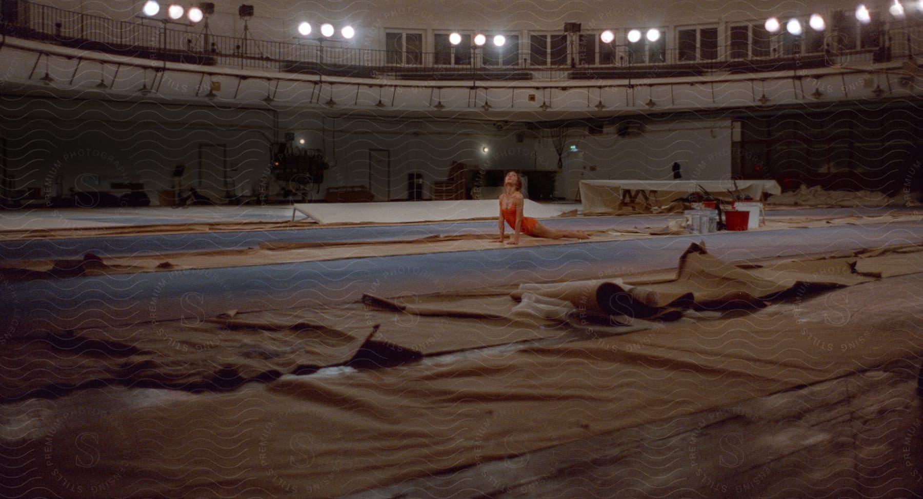 A young woman is stretching and doing gymnastics in an interior setting with wood flooring