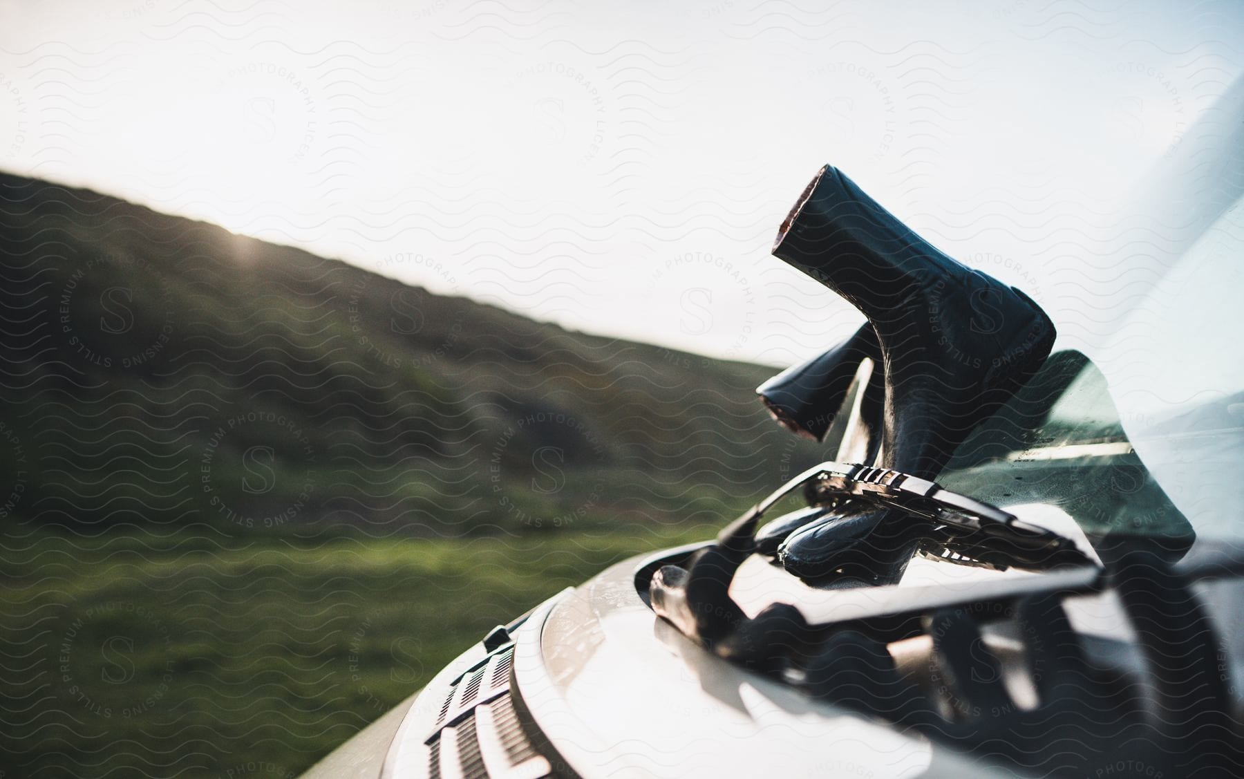 A pair of black rubber boots is stuck in the windshield wipers of a car