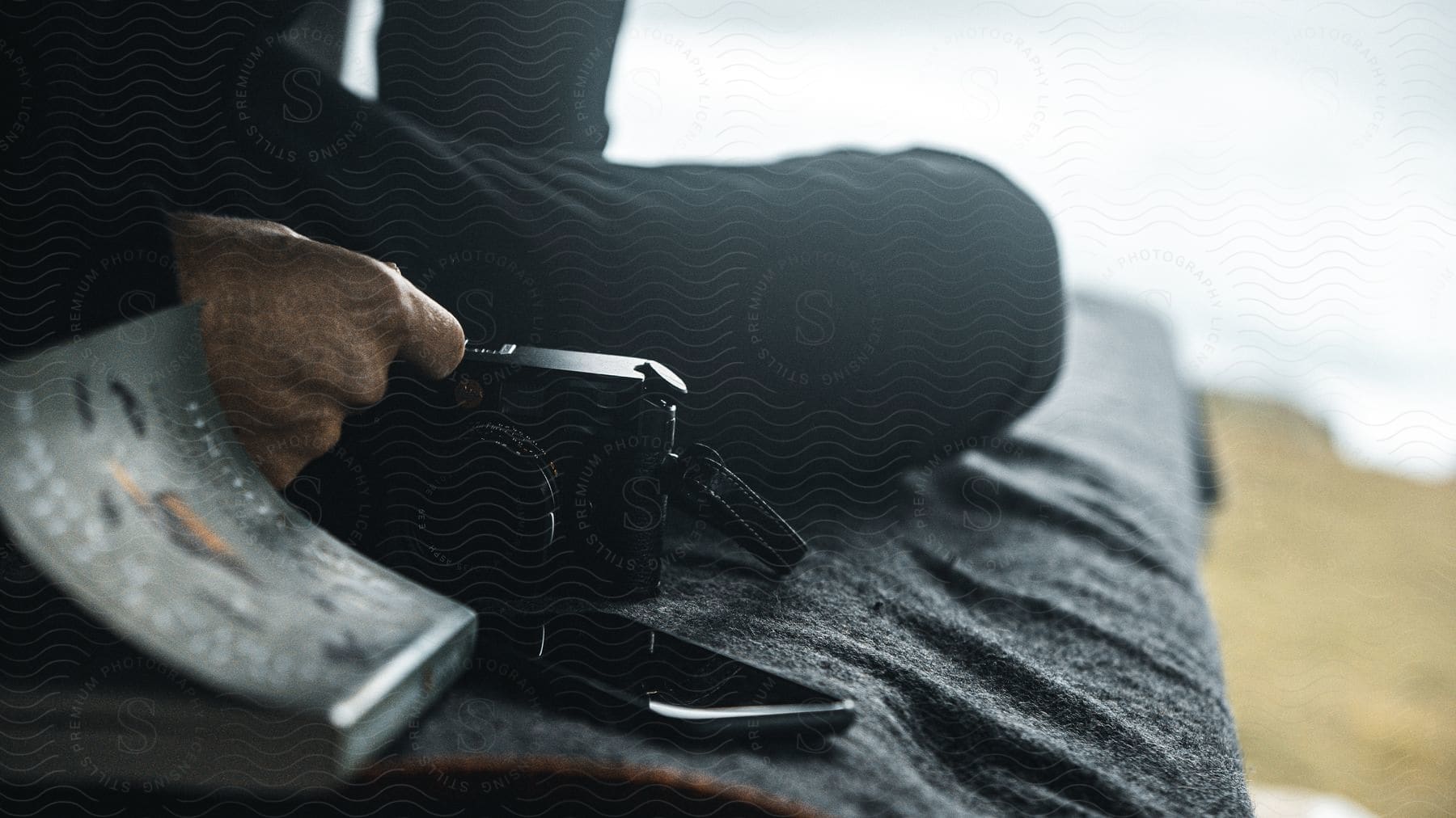 A man sitting on a couch with a mobile device digital camera and book neatly arranged by his side