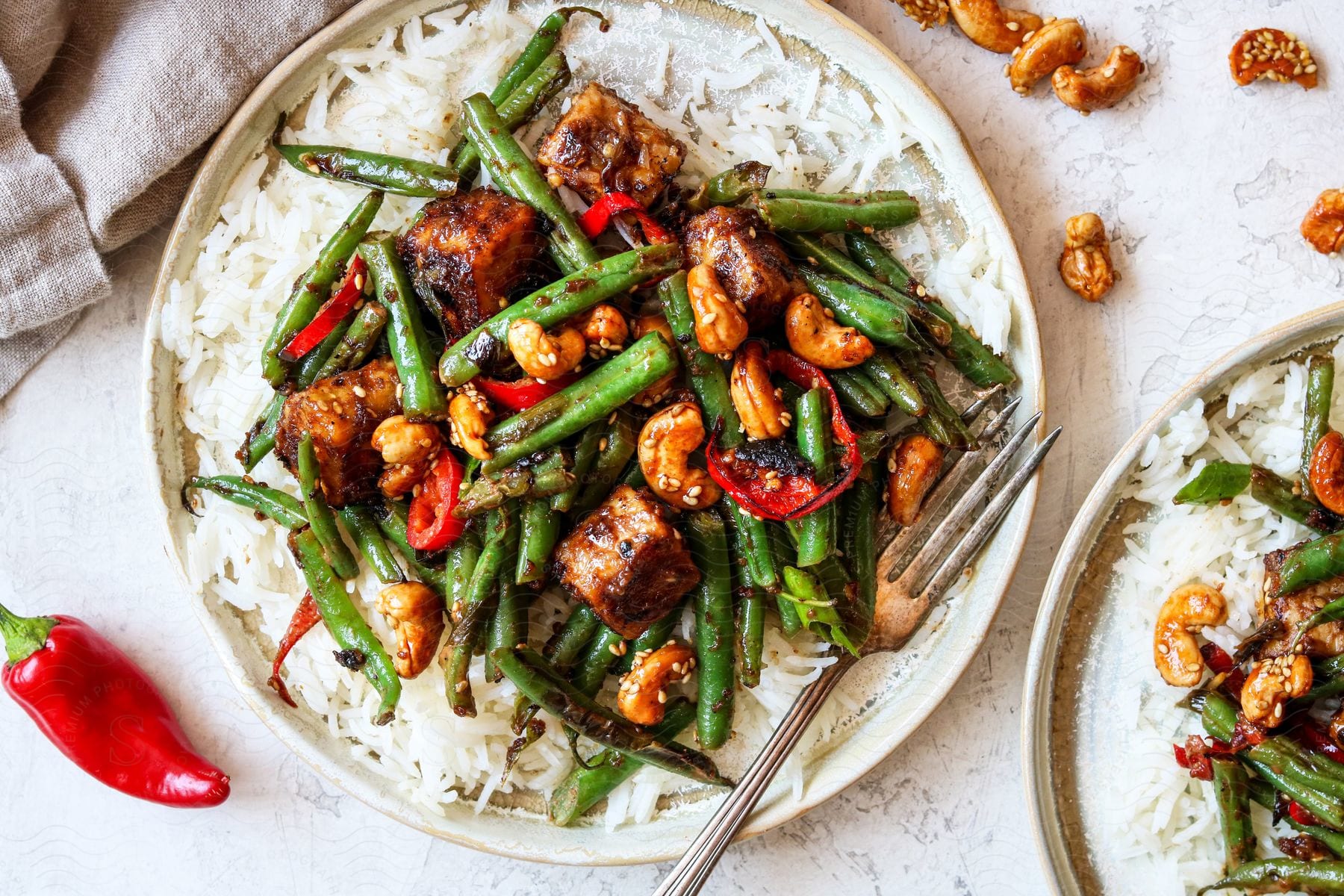 A dinner plate with beans peppers chicken cashews and rice topped with sauce and sesame seeds