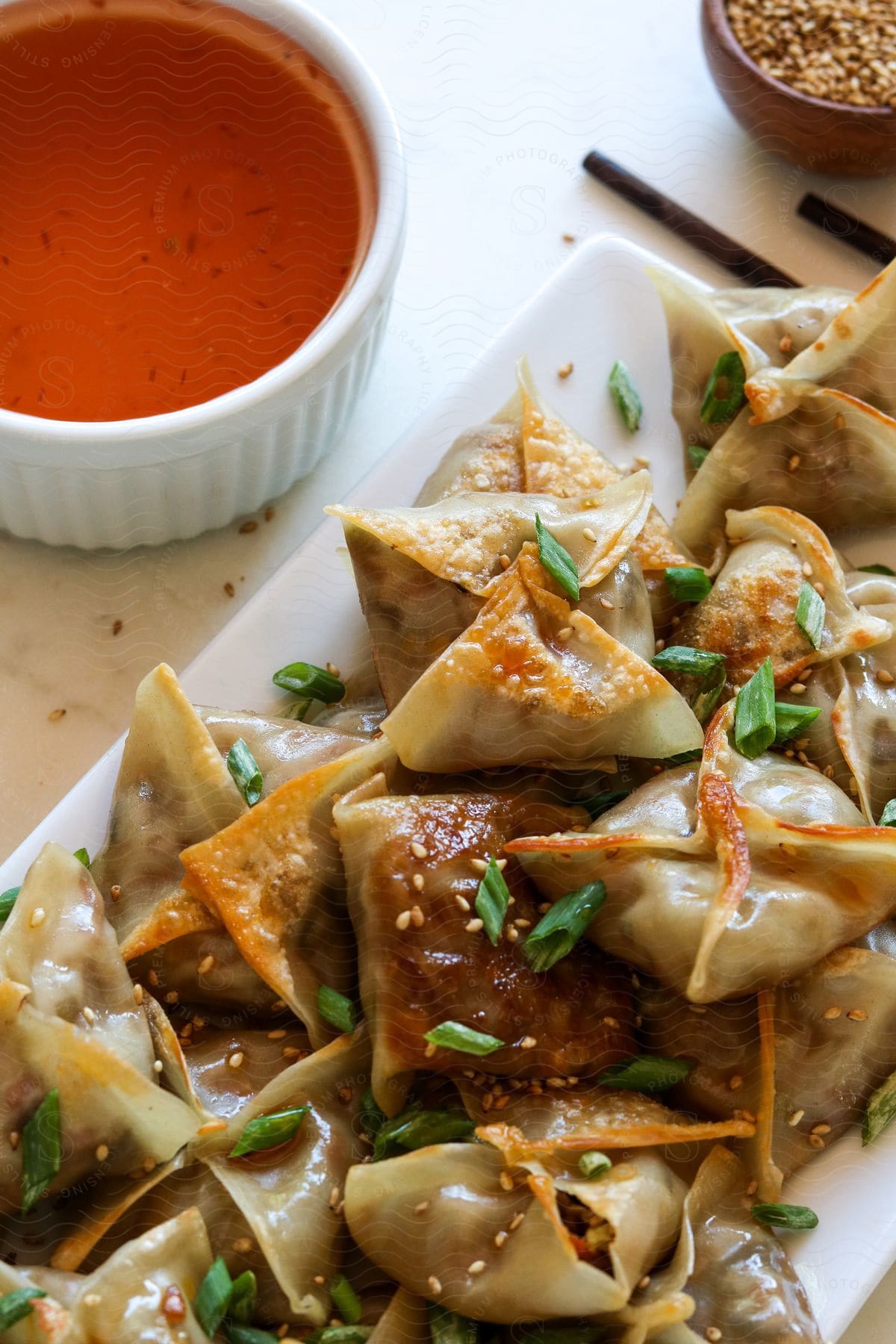 Close up of dumplings on a white ceramic dish on a table next to sauce