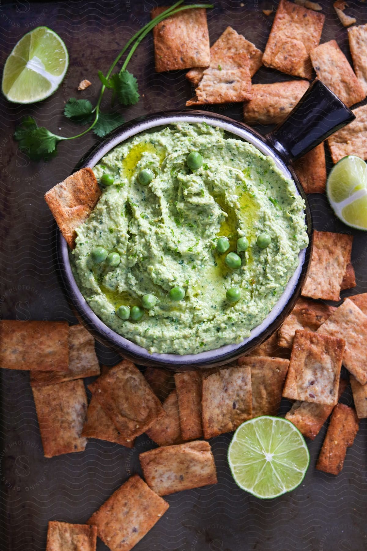 Crackers surround a dish of green dip