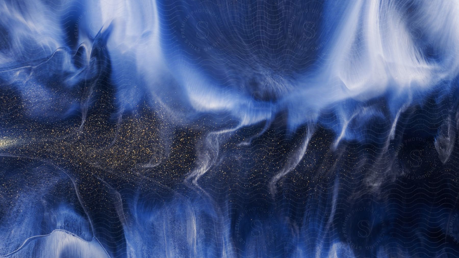 An abstract image with a gold speckled horizontal strip on a black background featuring blue and white colors blending together to create a smoky appearance