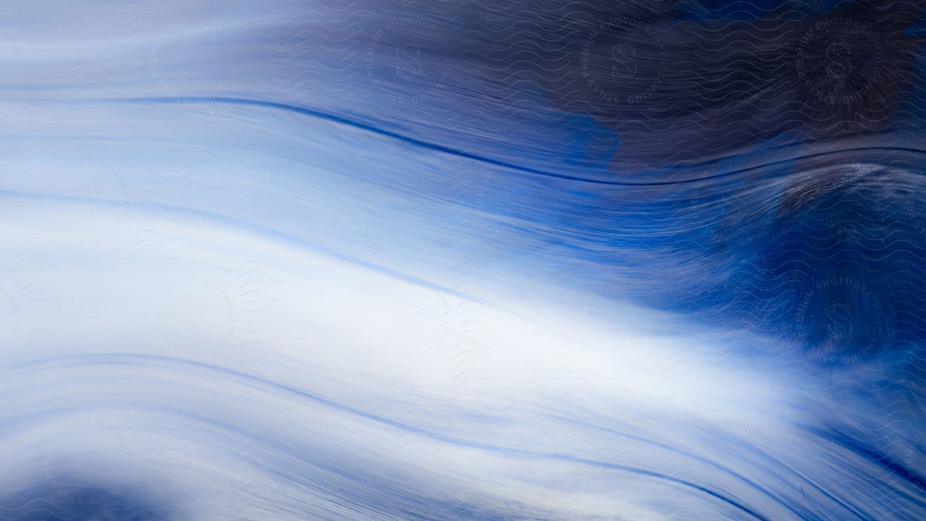 Blue and white liquids mix together in an abstract image