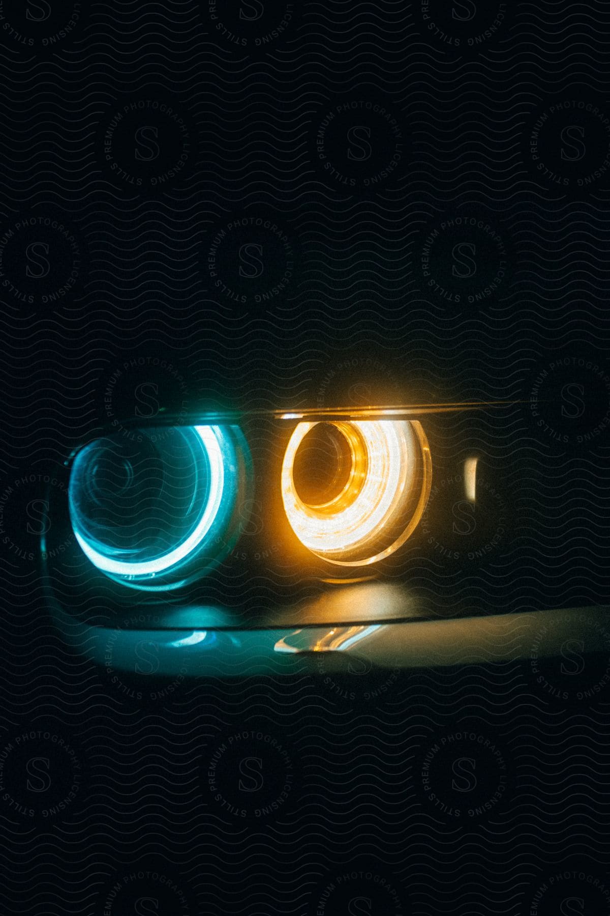 A closeup of orange and blue halo headlights on a car at night