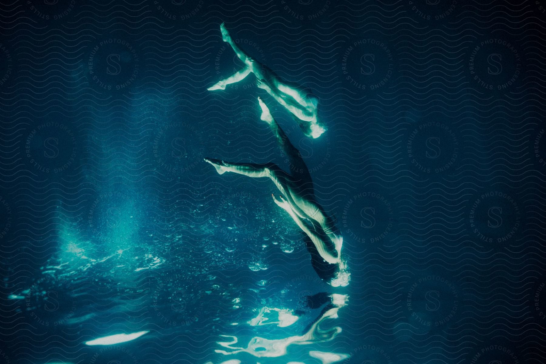 Two Women Swimming Underwater Upside Down