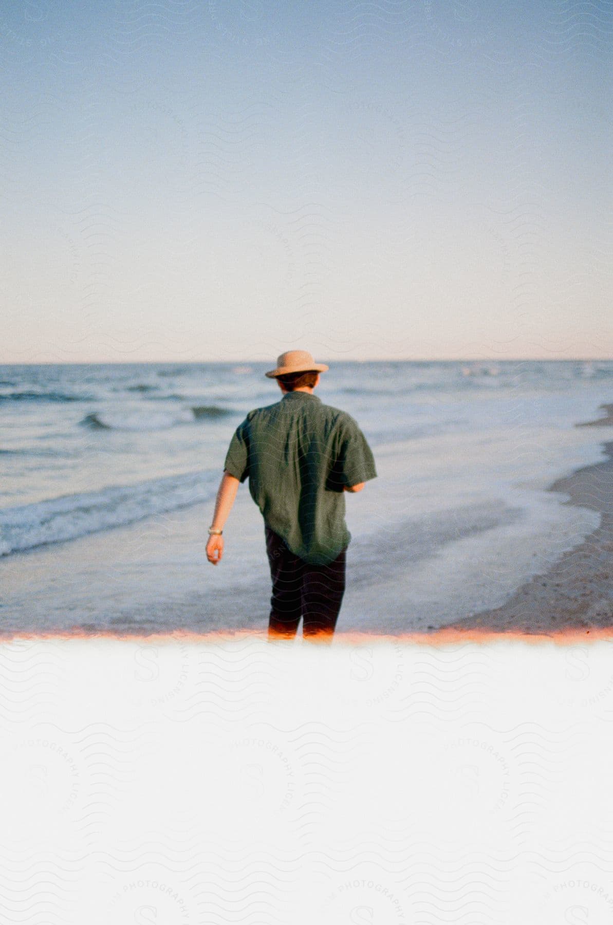 A man walking along the beach as the water moves closer to the shore