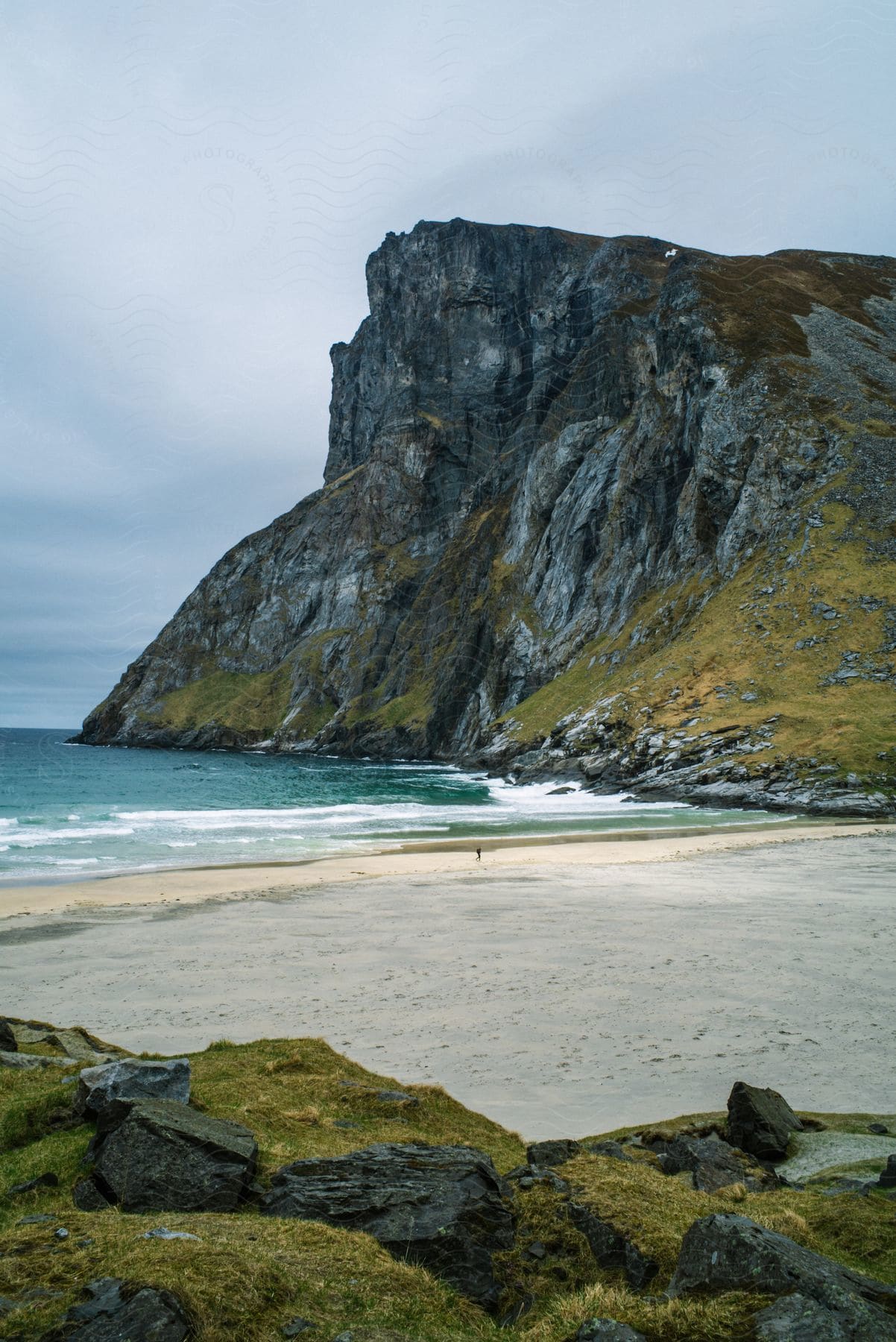 The tide comes in on a beach with rocky mountainous formations