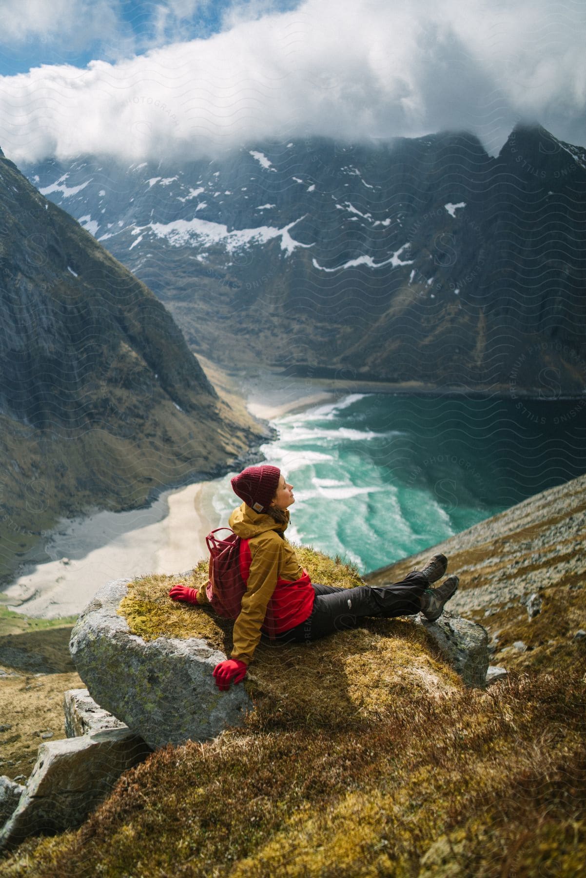 A person in nature surrounded by mountains water and vegetation