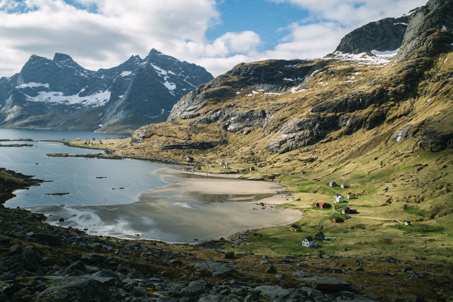 Aerial view of houses spreading out over a lake bank and rugged mountains in lofoten norway