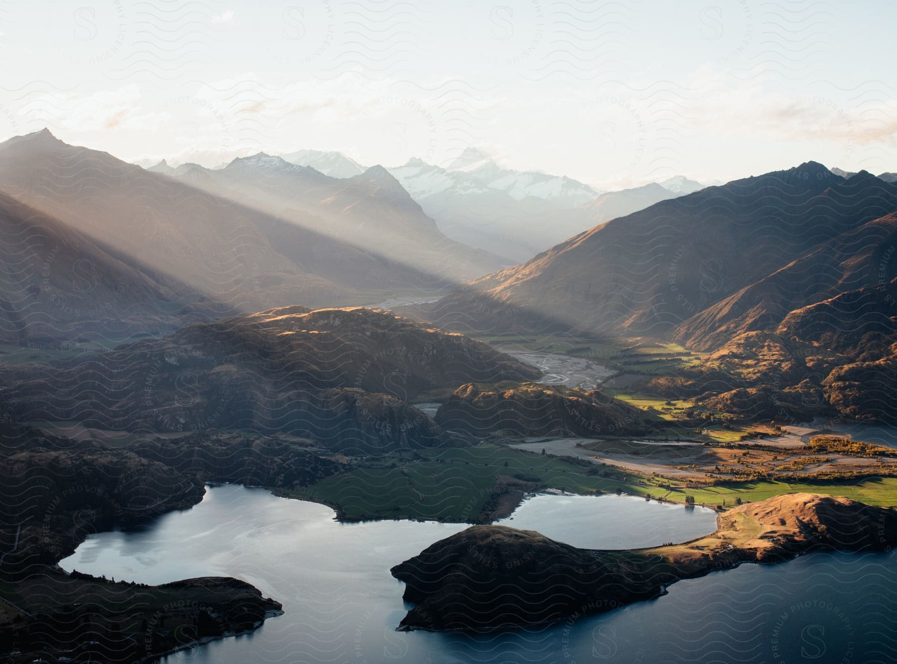 A serene aerial view of a mountainous landscape with a lake and watercourse