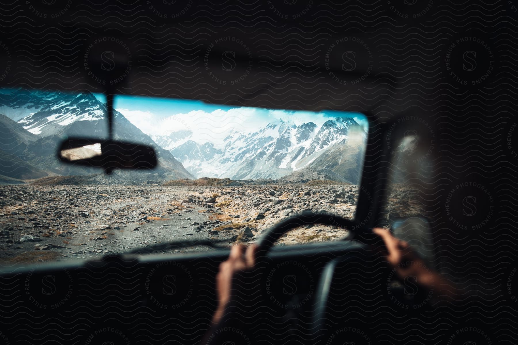 A person is driving their vehicle near a mountainous landscape