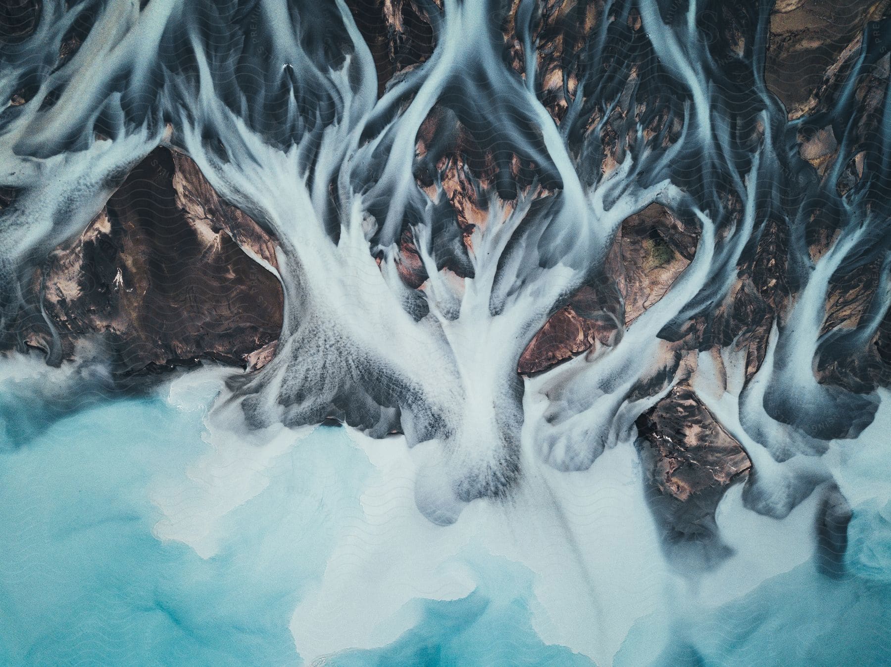 Rivers flow out of a glacier seen from above in the mountains of new zealand