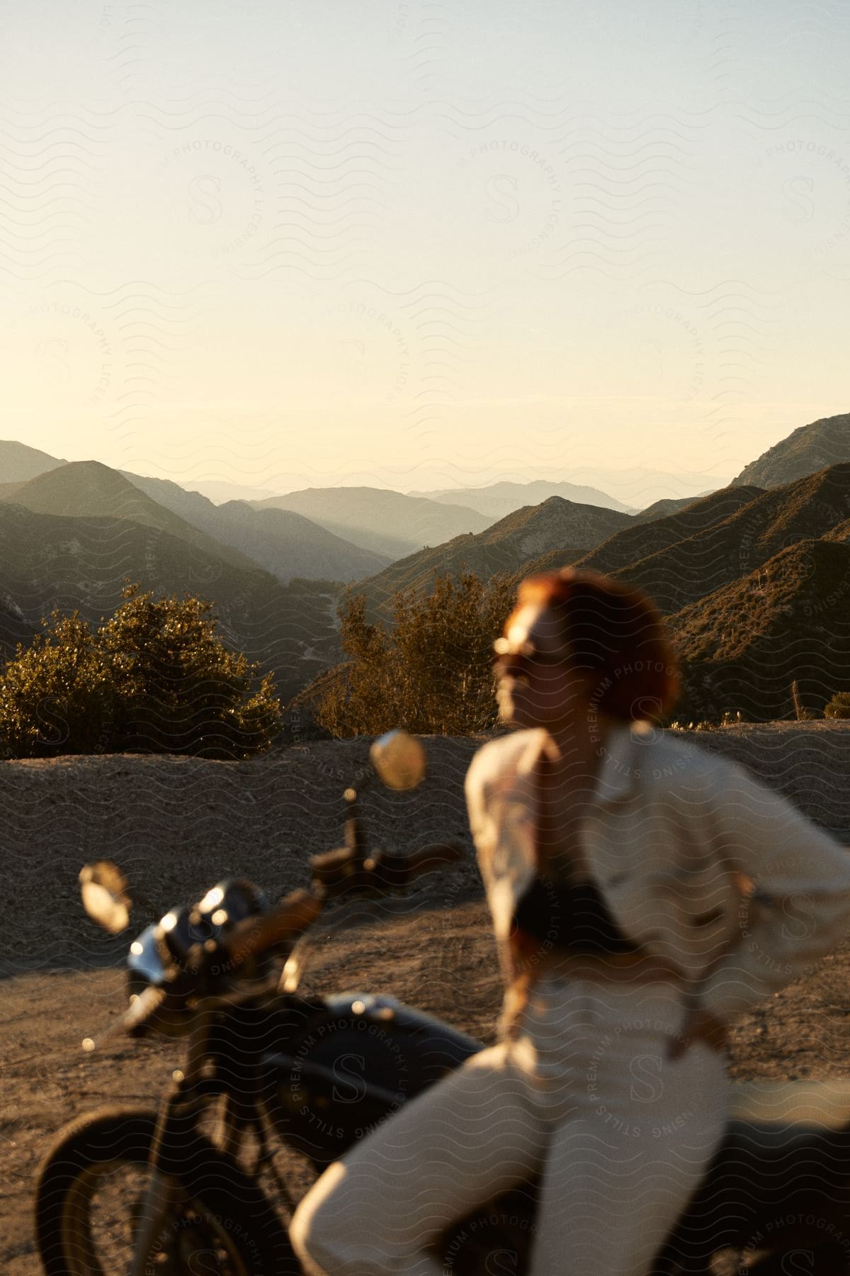 A woman sitting on a motorcycle outdoors at dusk