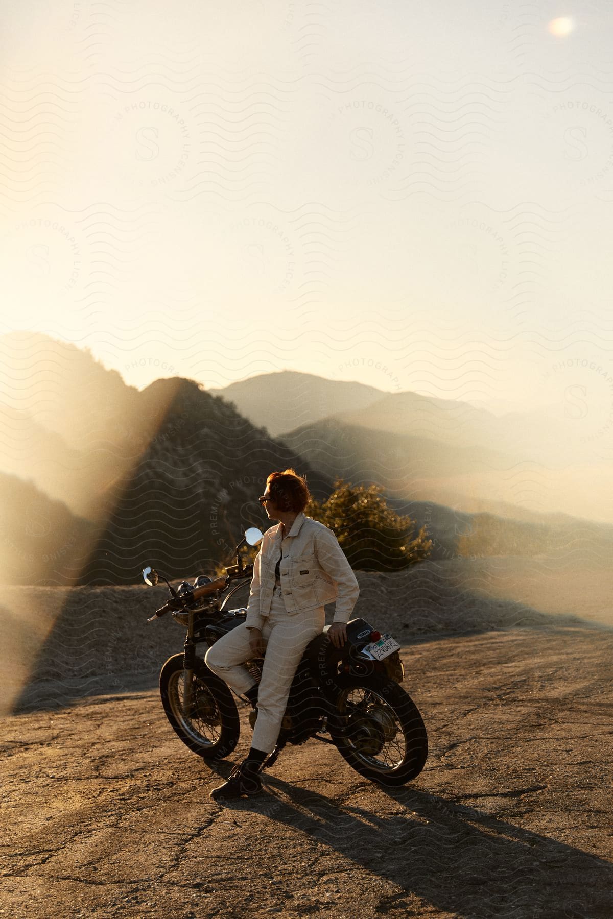 A man rides a motorcycle in the mountains at sunset