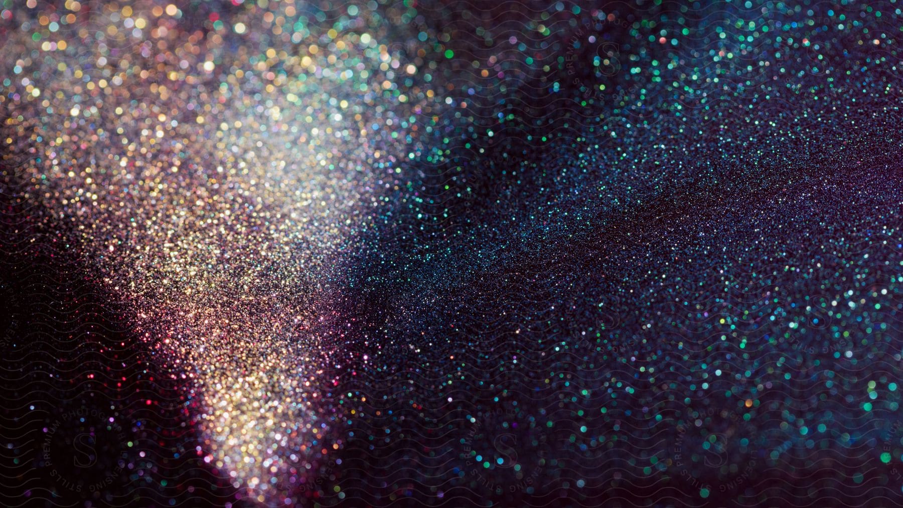 Stock photo of colorful glowing dots and circles resembling scattered glitter on a dark background