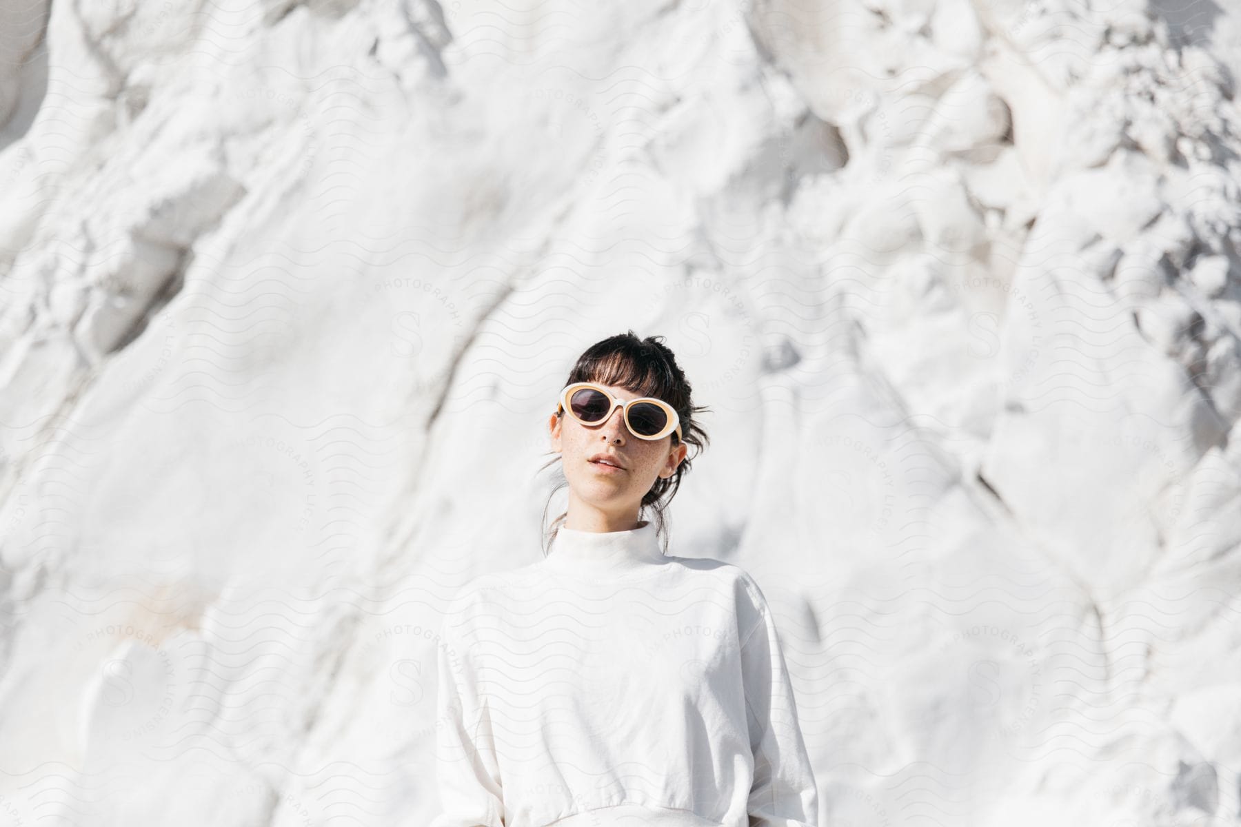 A woman with a sleeve and sunglasses smiling in the snow