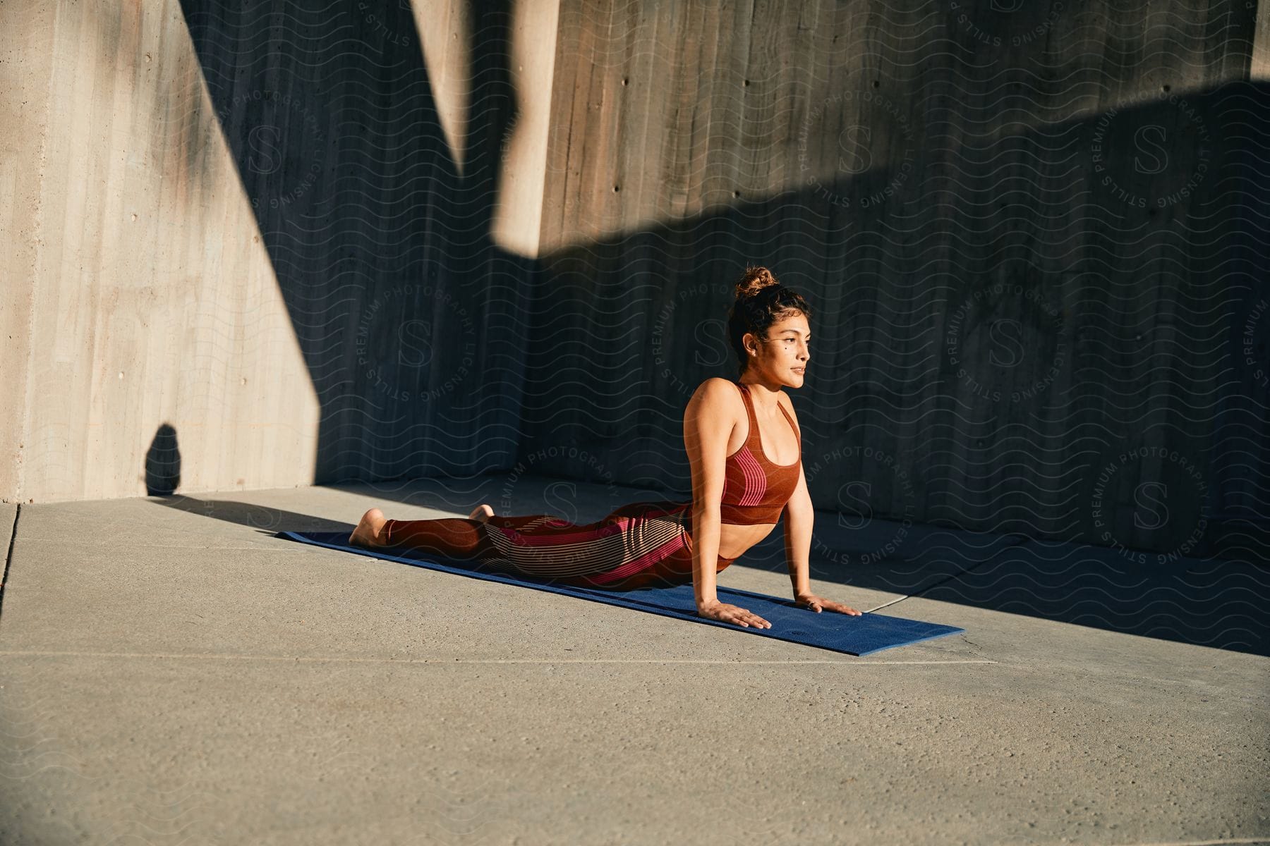 Woman in sportswear doing yoga stretching indoors on wooden flooring