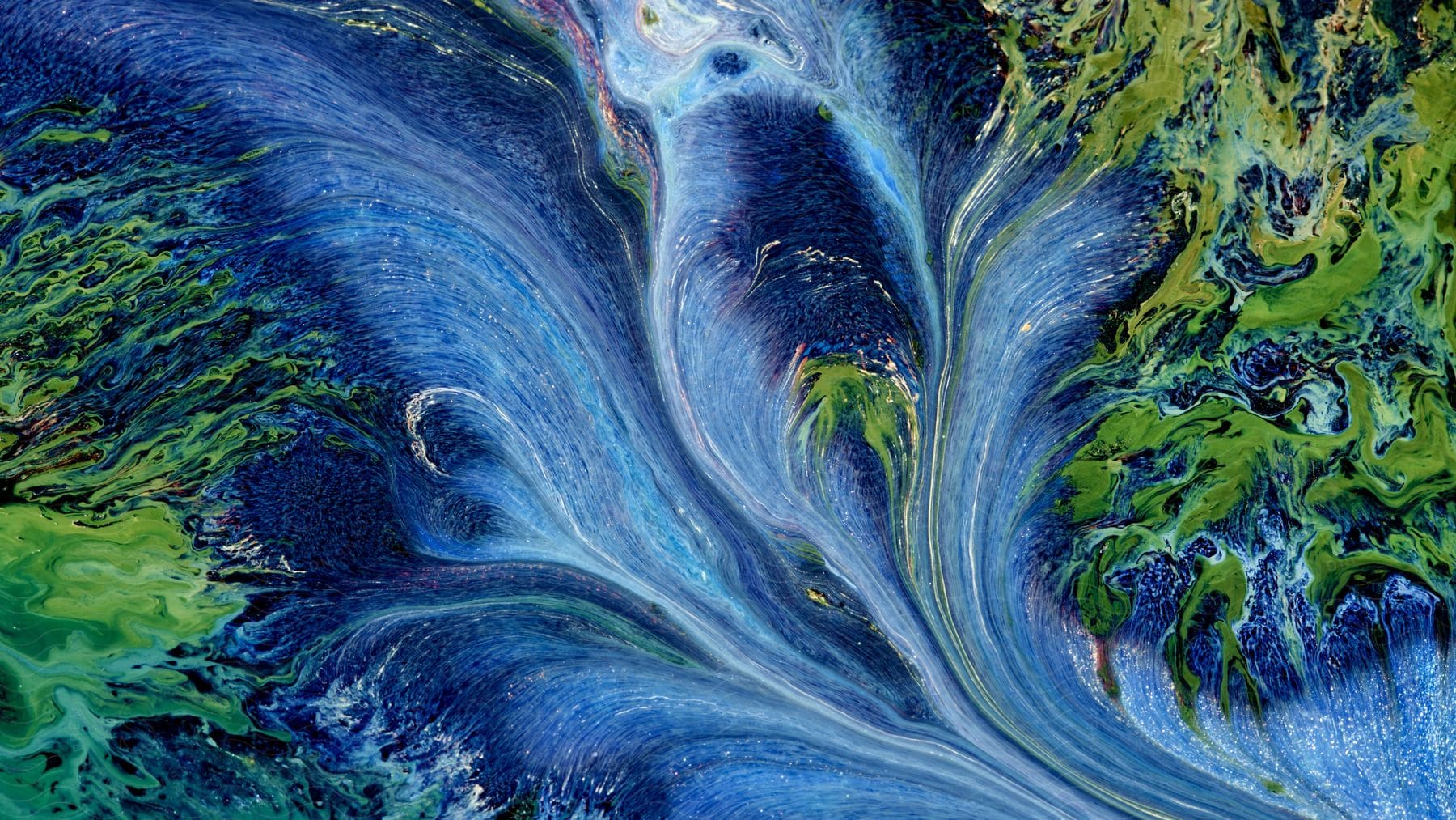 An abstract mixture of blue and green colors resembling miniature landscapes created with paint on a piece of paper