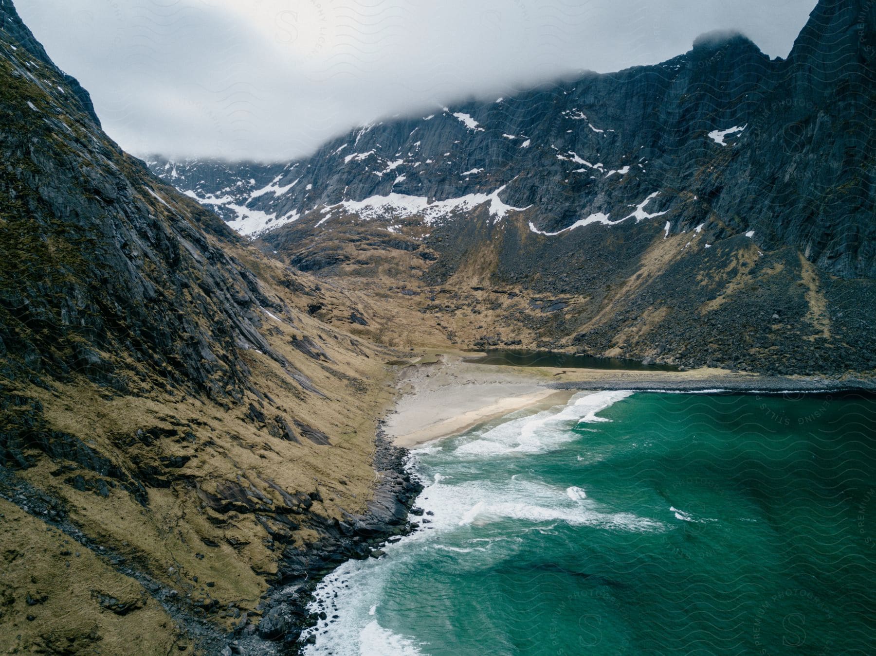 Waves crash on a small beach in a valley surrounded by mountains