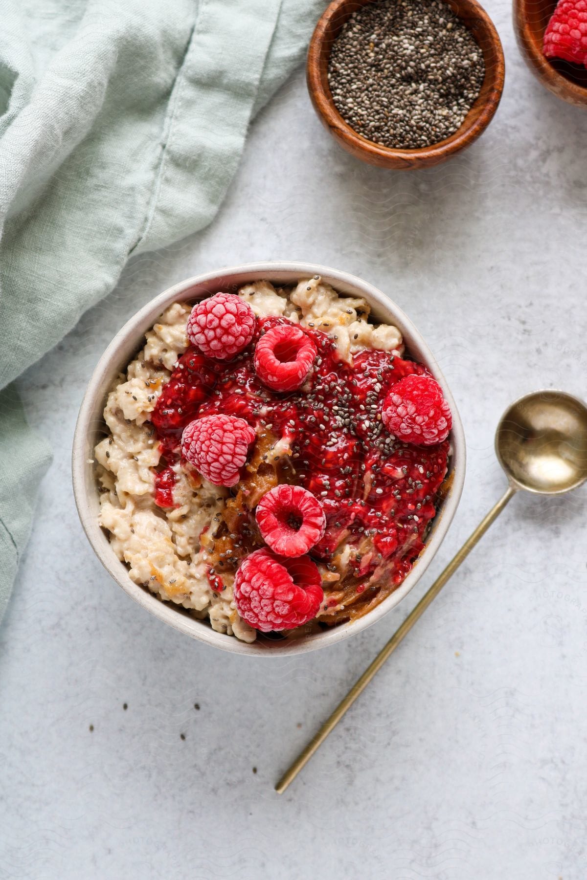 A bowl of cereal and berries sits on a table seen from above