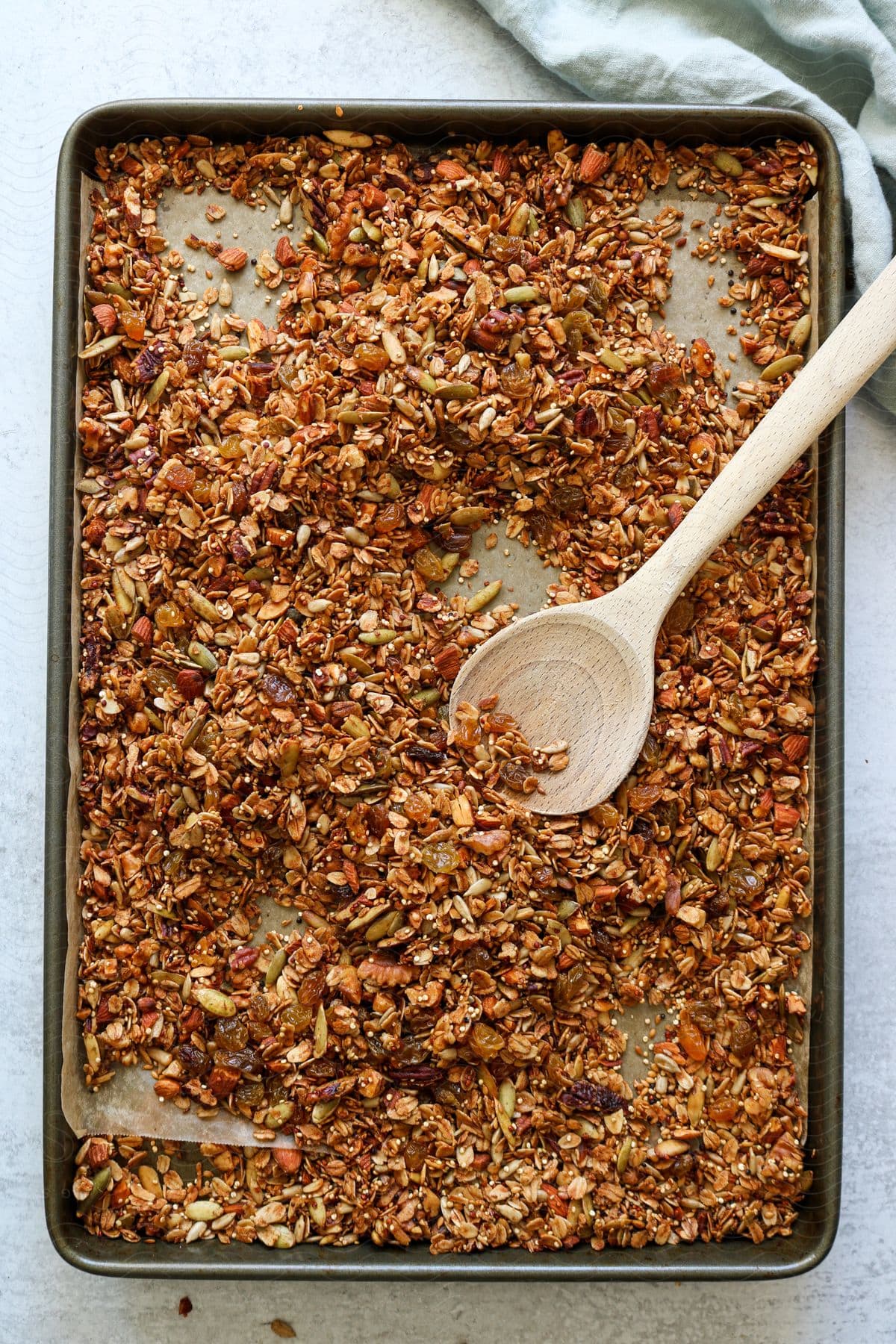 A wooden spoon rests on a pan of granola