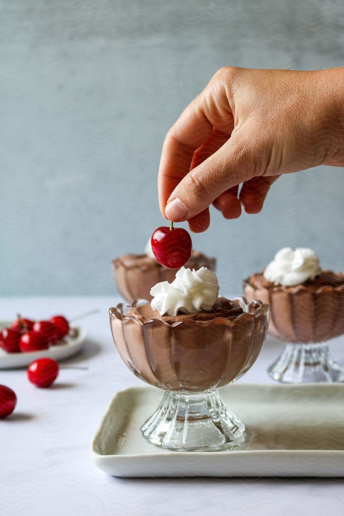 A red cherry is placed into the whipped topping on a chocolate dessert