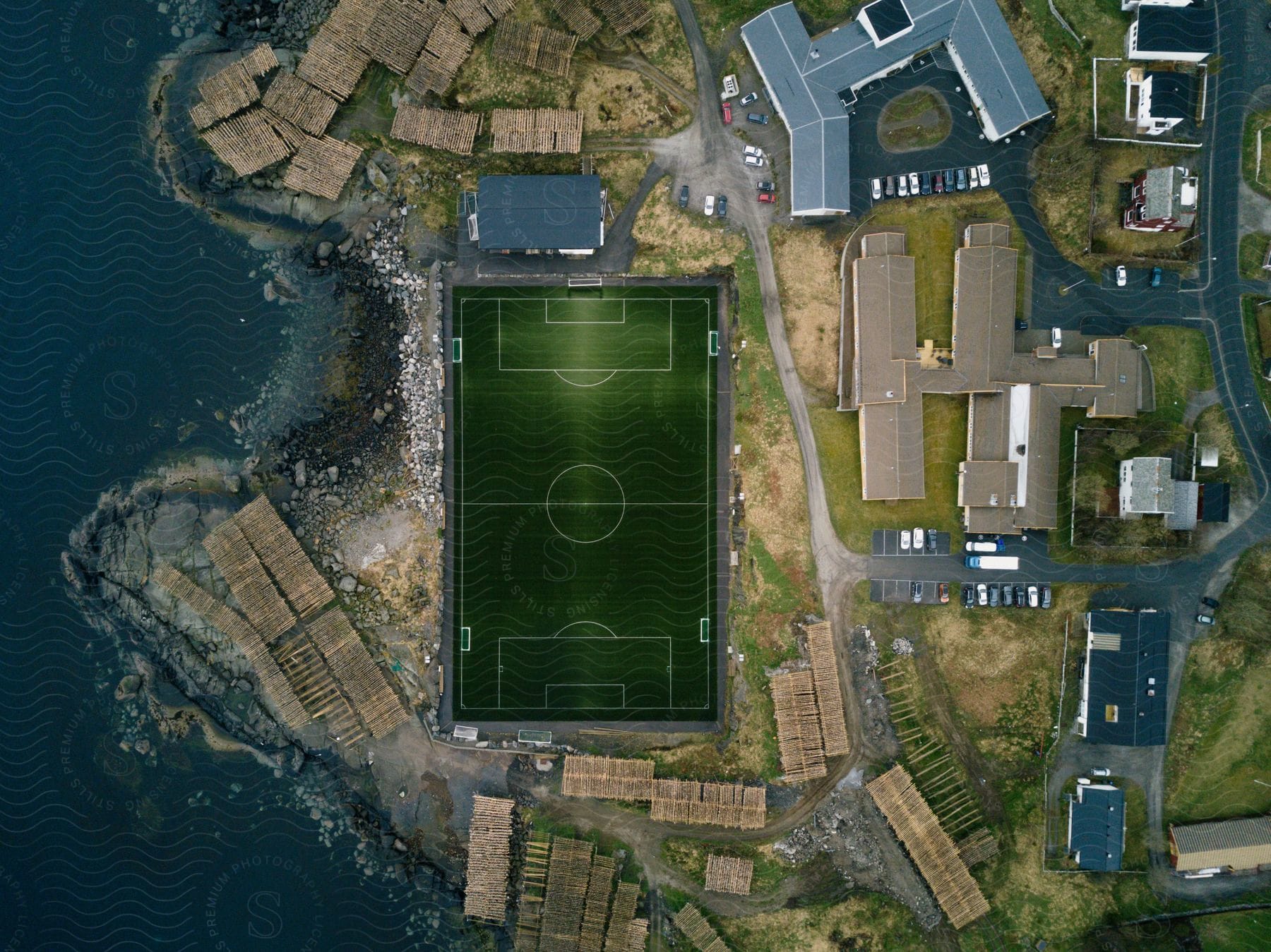 Soccer field next to buildings near the rocky coast