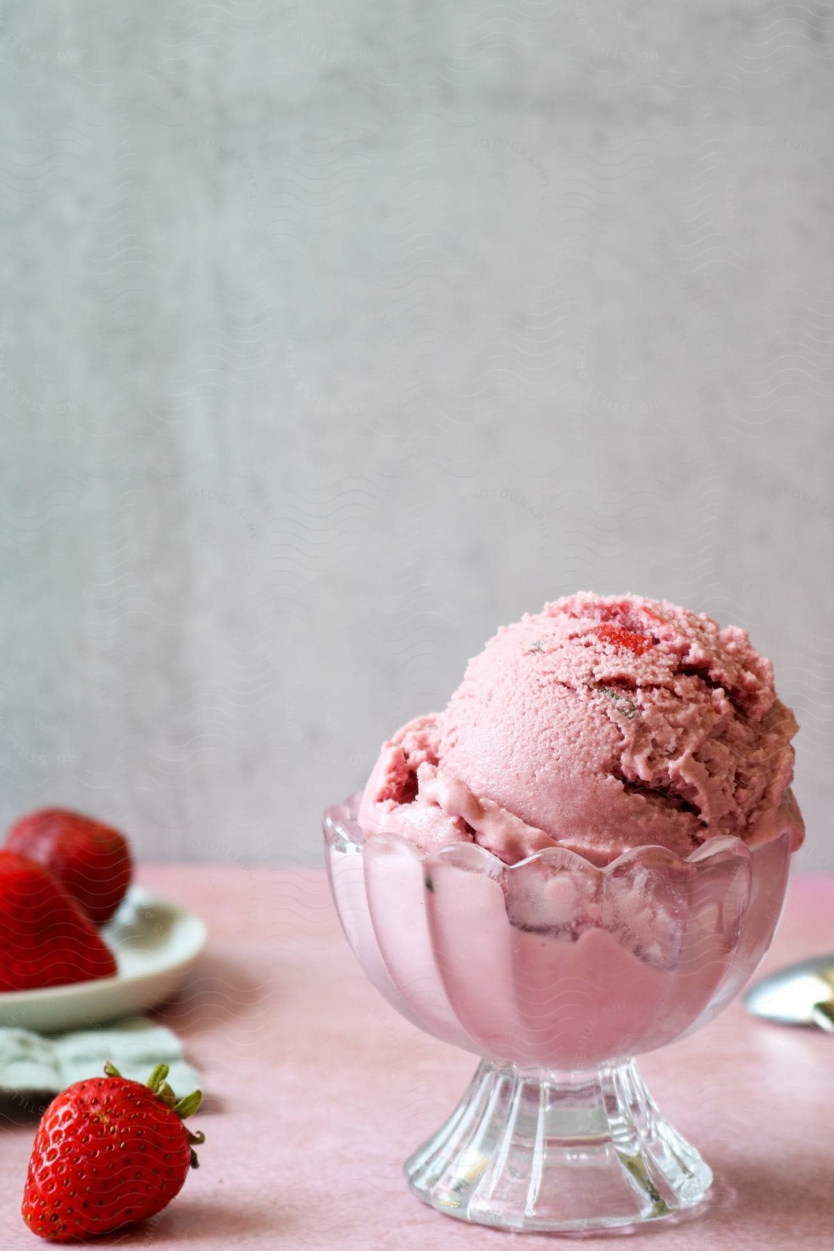 Strawberry ice cream in a serving dish with fresh strawberries