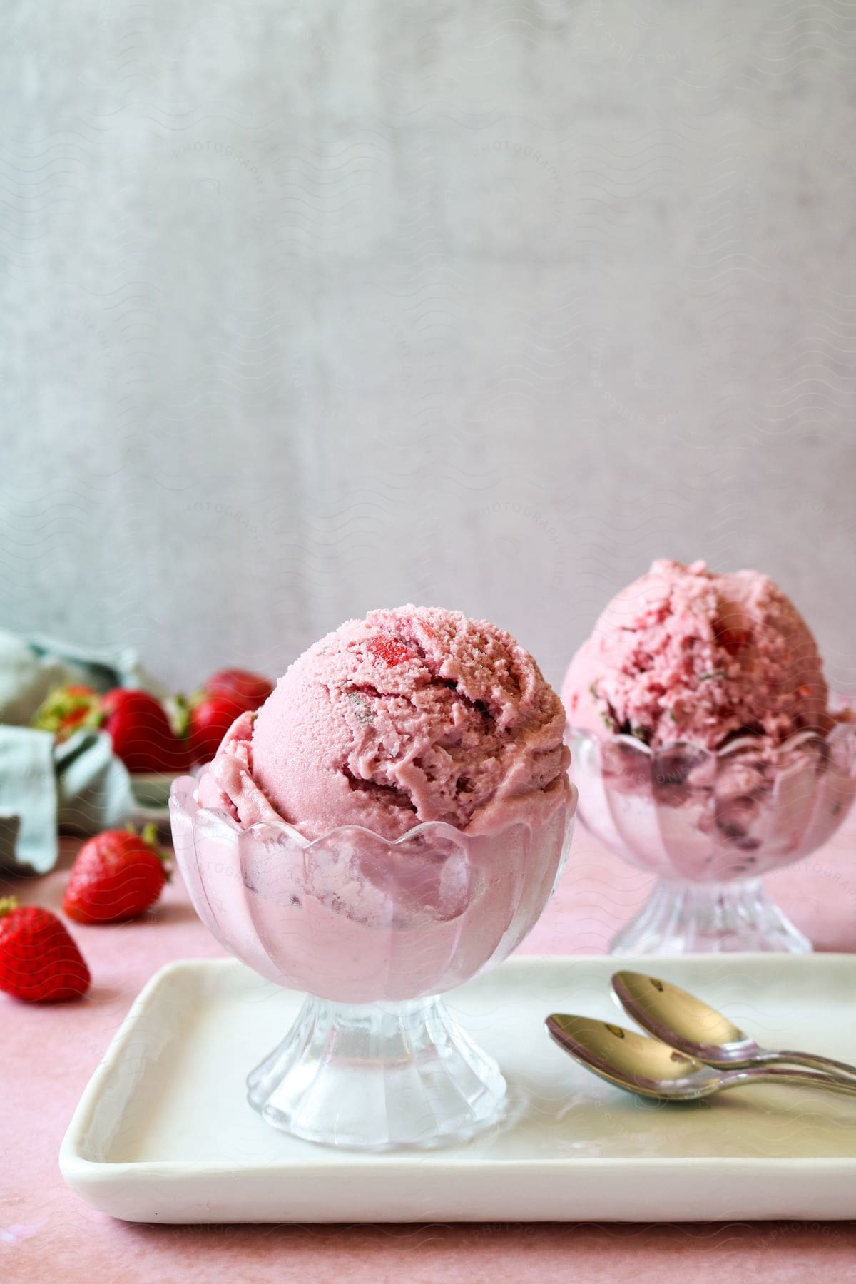 Cups with scoop of pink ice cream on a table