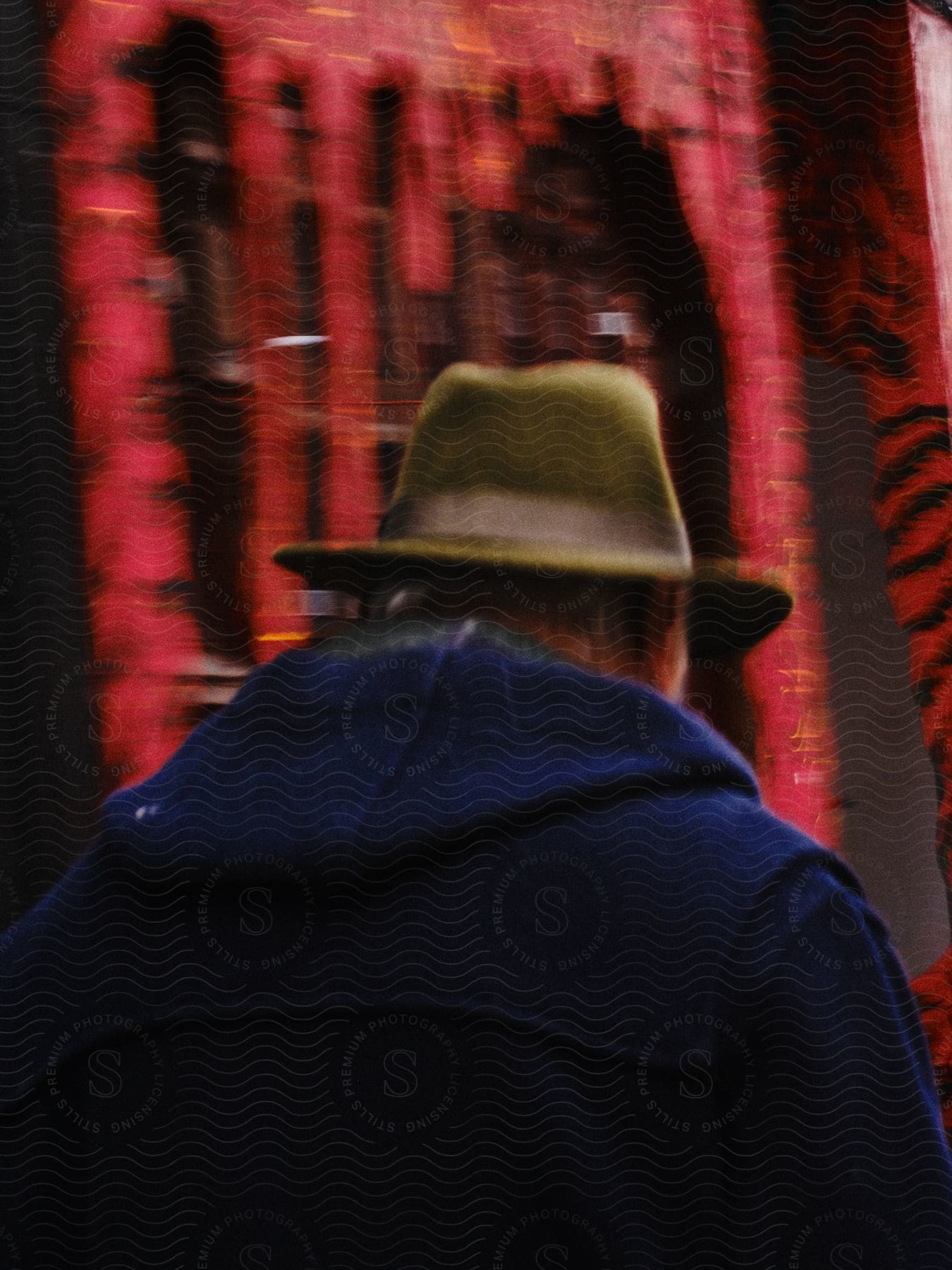 A person wearing a coat and a fedora hat