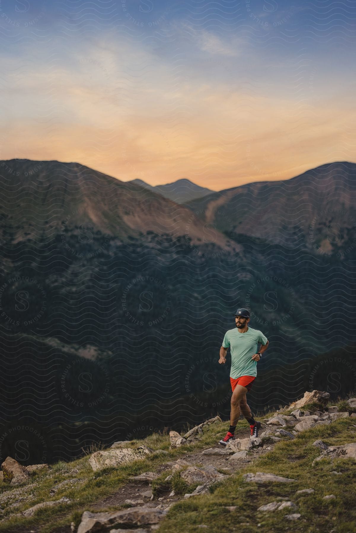 A determined man in a red shirt green top and cap is running on a mountain trail