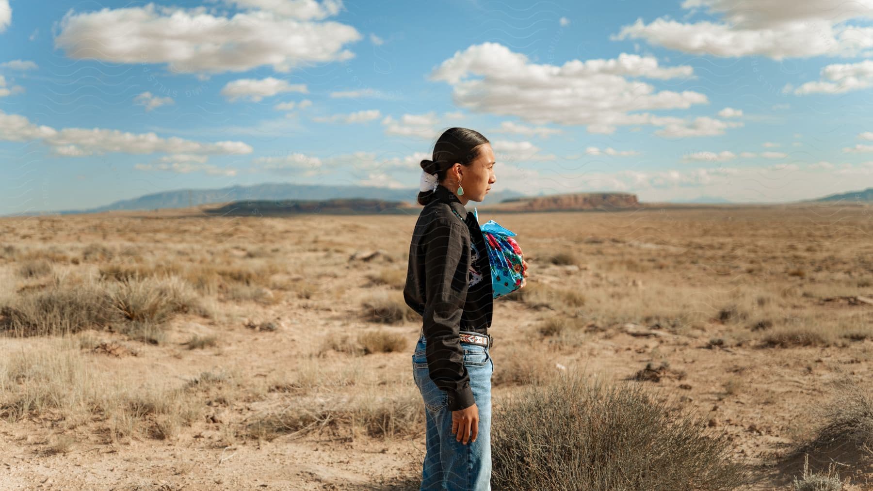 A native american woman stands in the desert observing the golden grass under the sun