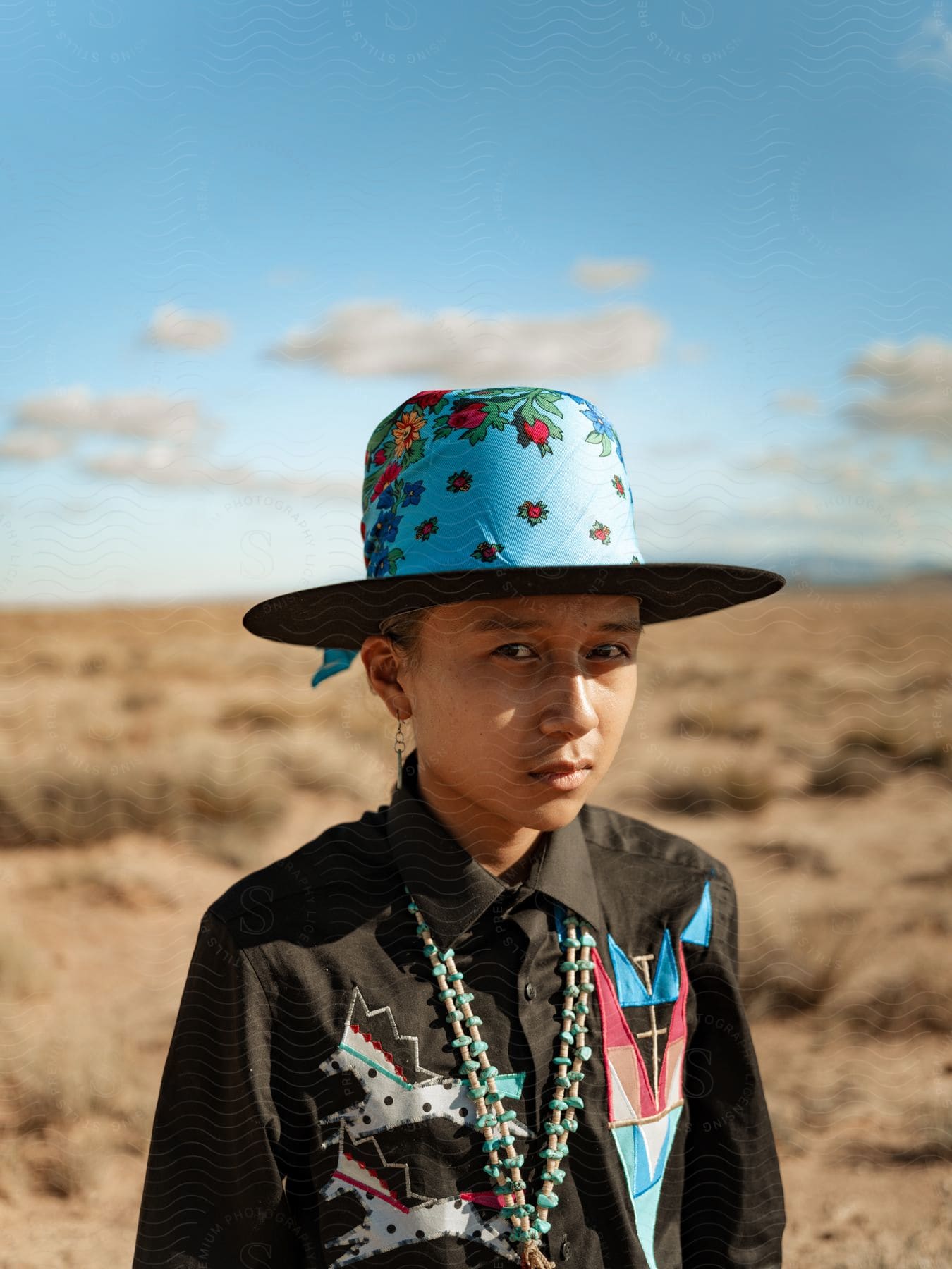 A person wearing a sun hat and necklace in a natural setting