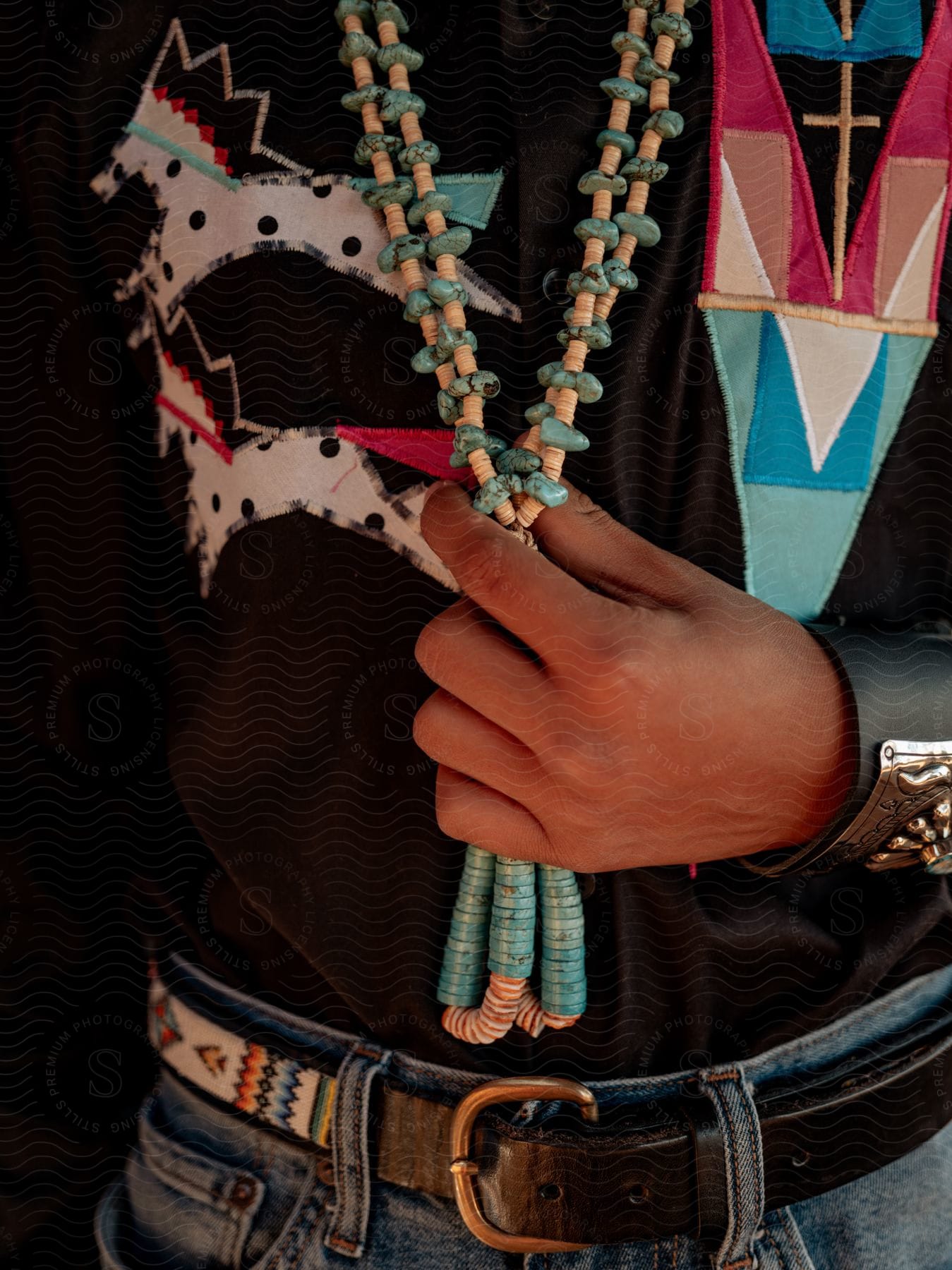 A person wearing jewelry including a necklace with beads with their hand on their waist