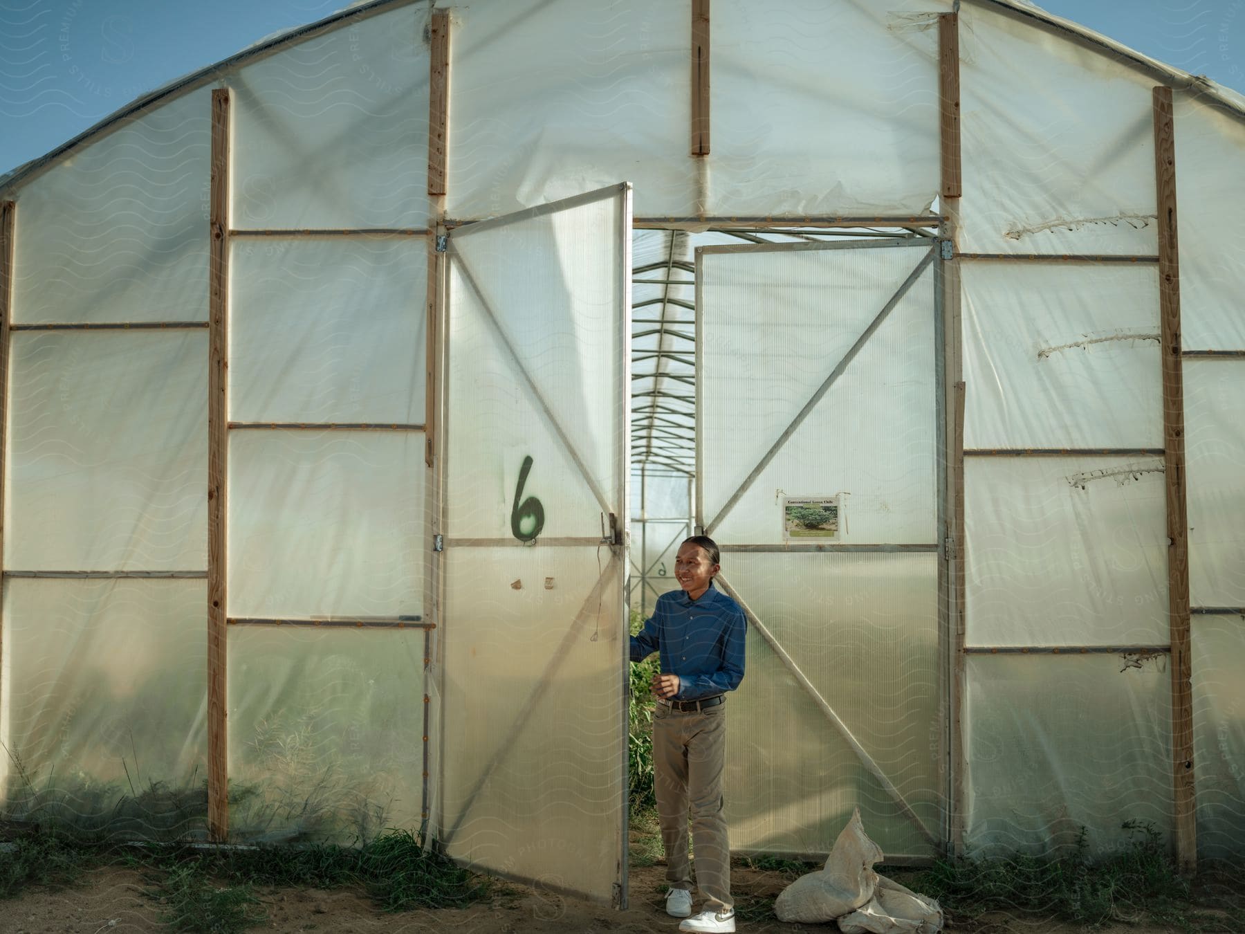 A young man steps out of the door of a greenhouse in red mesa az navajo nation