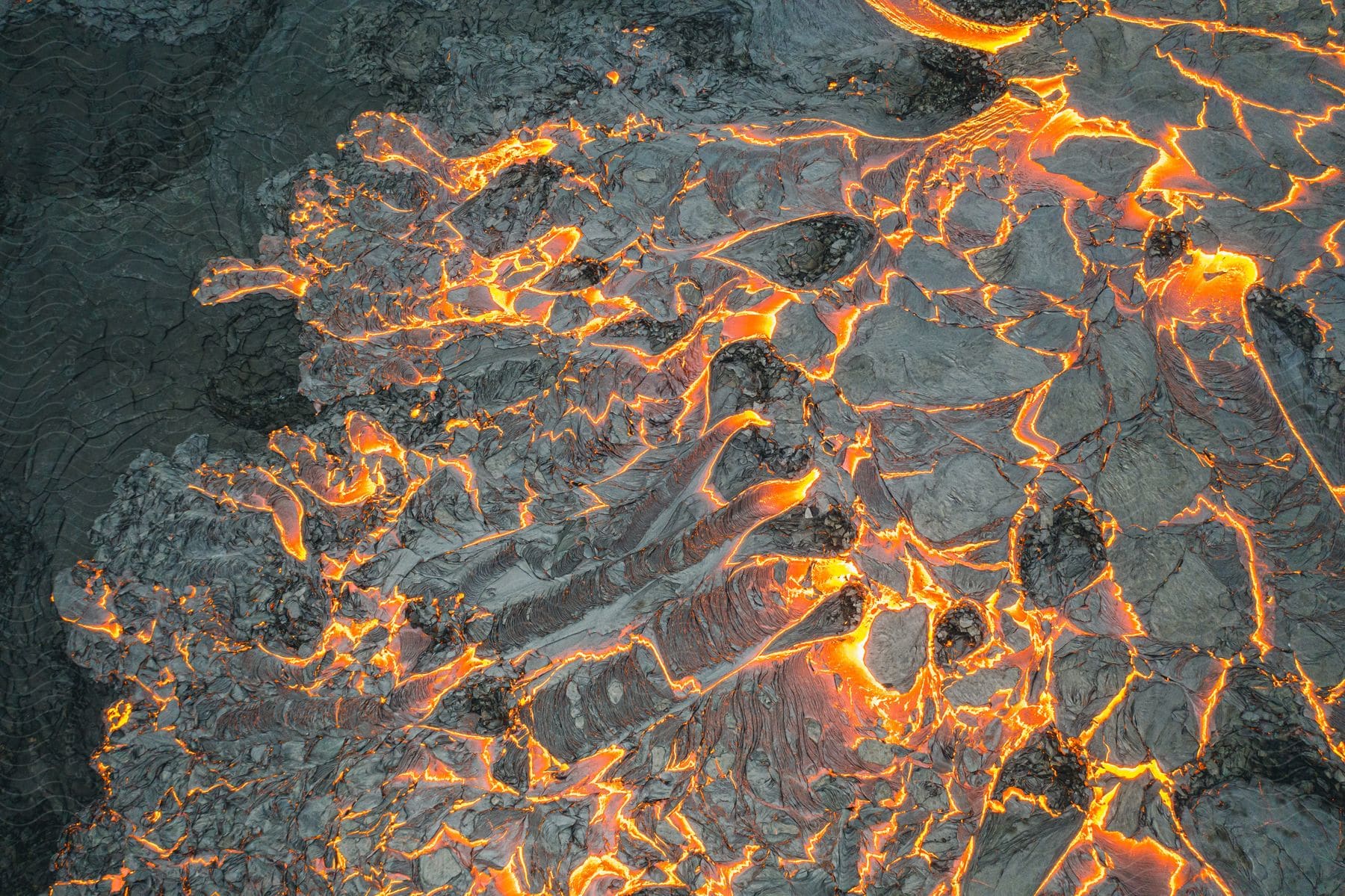 Hot lava glows as it flows from an erupting volcano