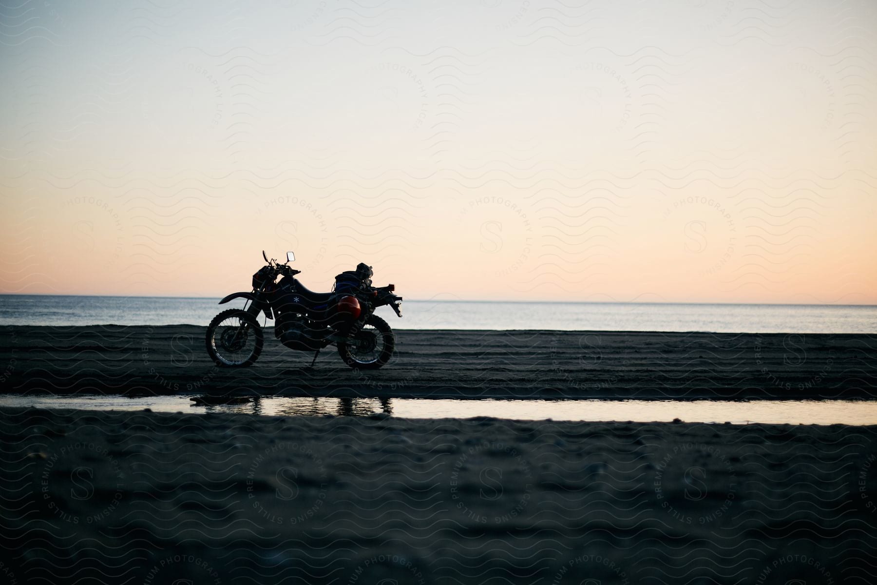 A motorcycle parked on a beach at dusk