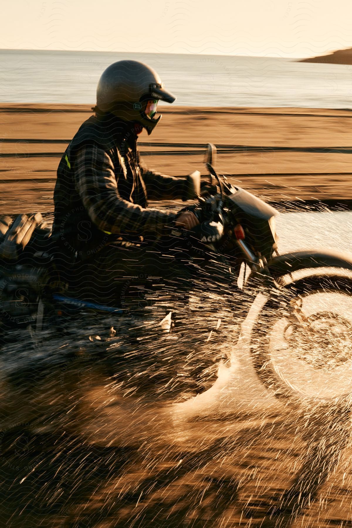 A person riding a motorcycle through water on a sandy beach