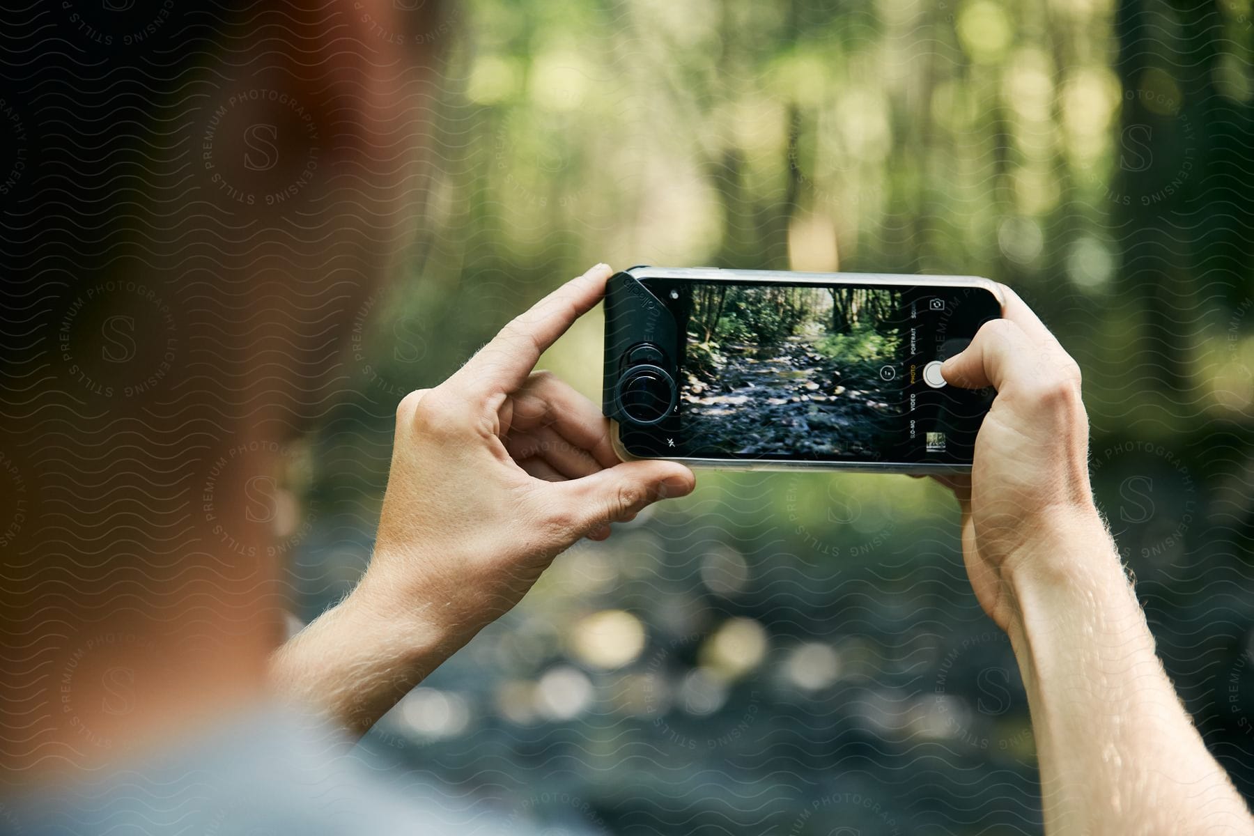 A man stands in the woods holding a camera