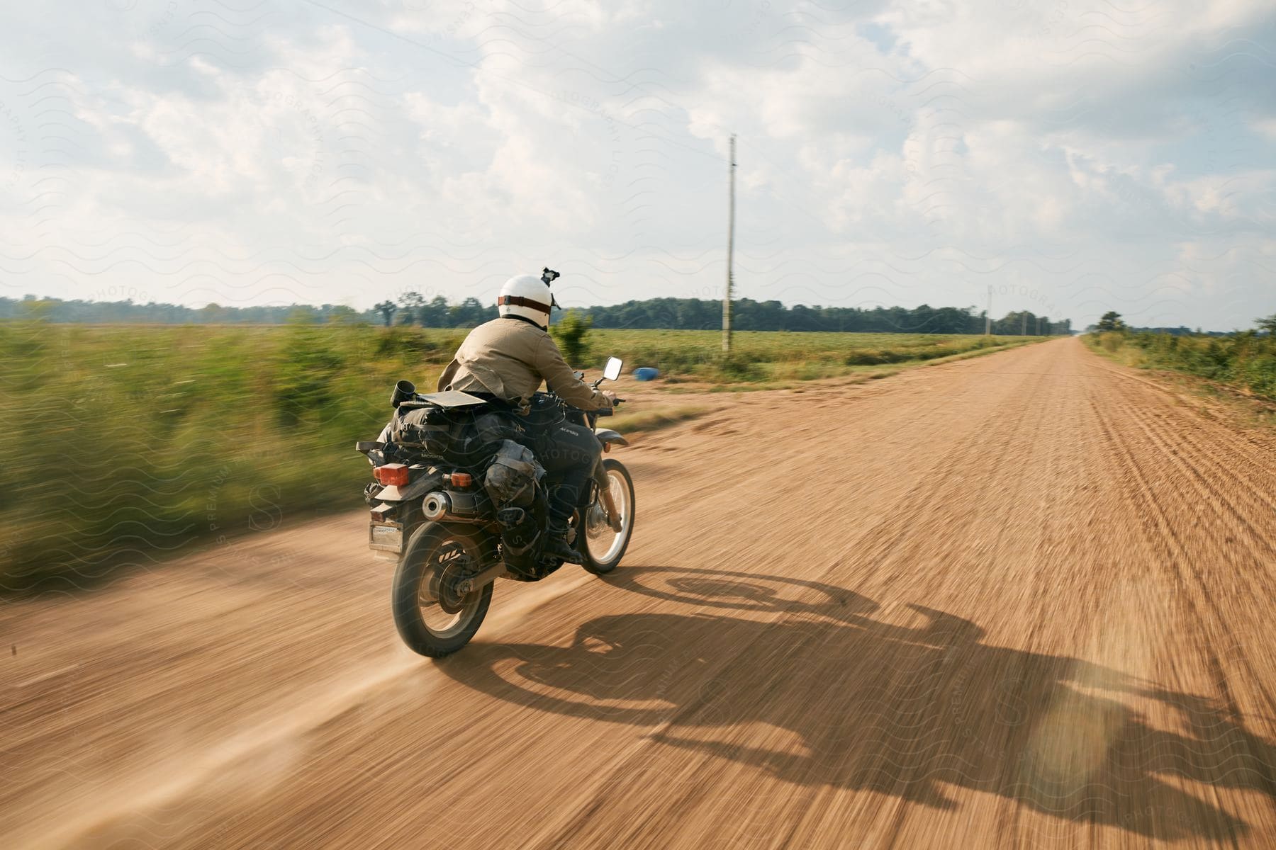 A man riding a motorcycle under a clear sky on a grassy road