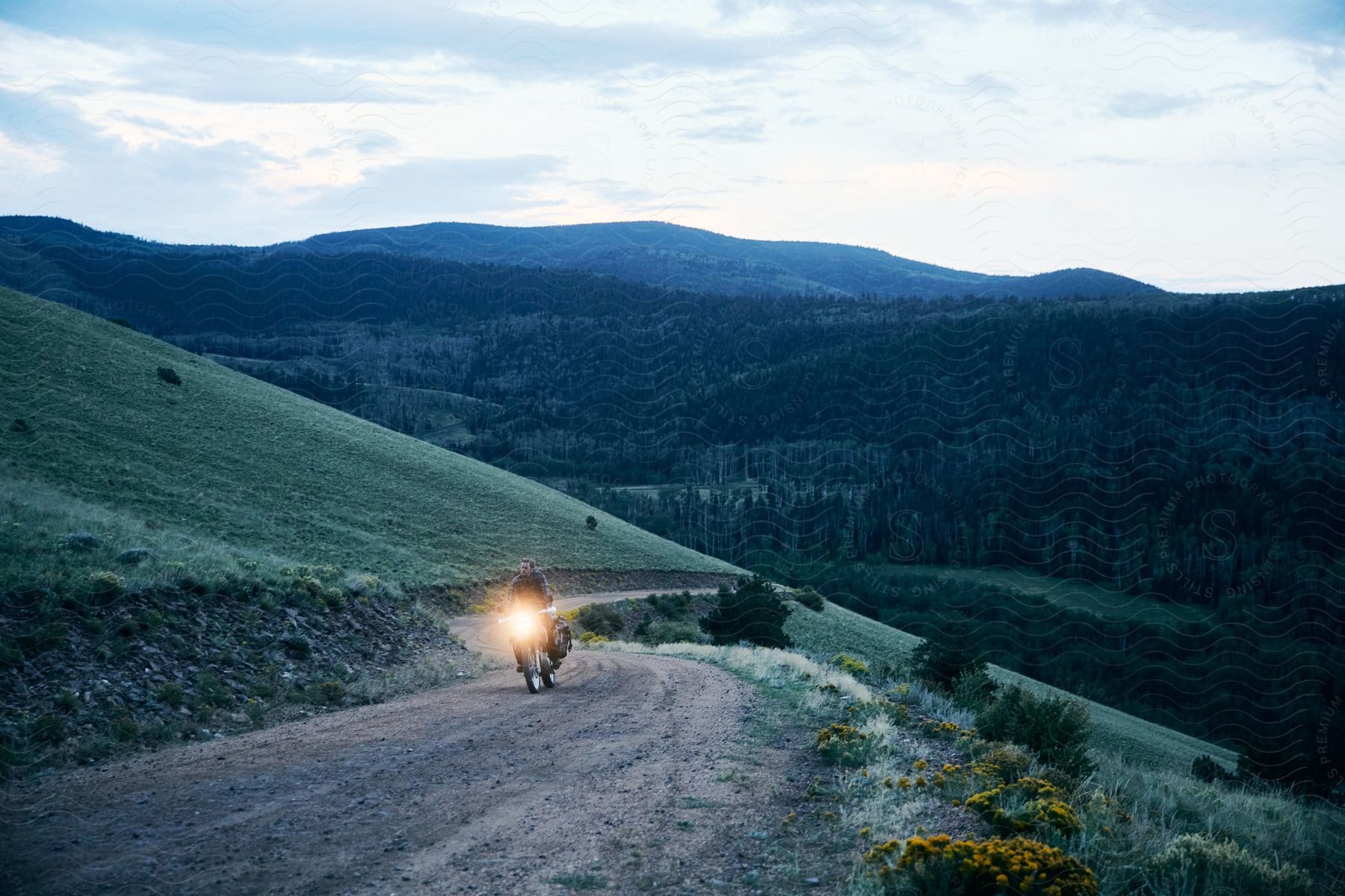 Mountain landscape with a narrow road crossed by a motorbike with headlights on