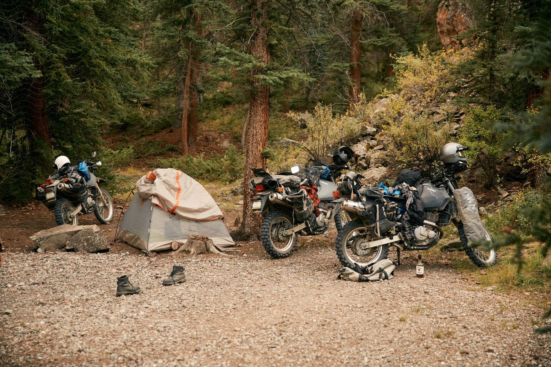 A person with a motorcycle near a tent in an outdoor setting