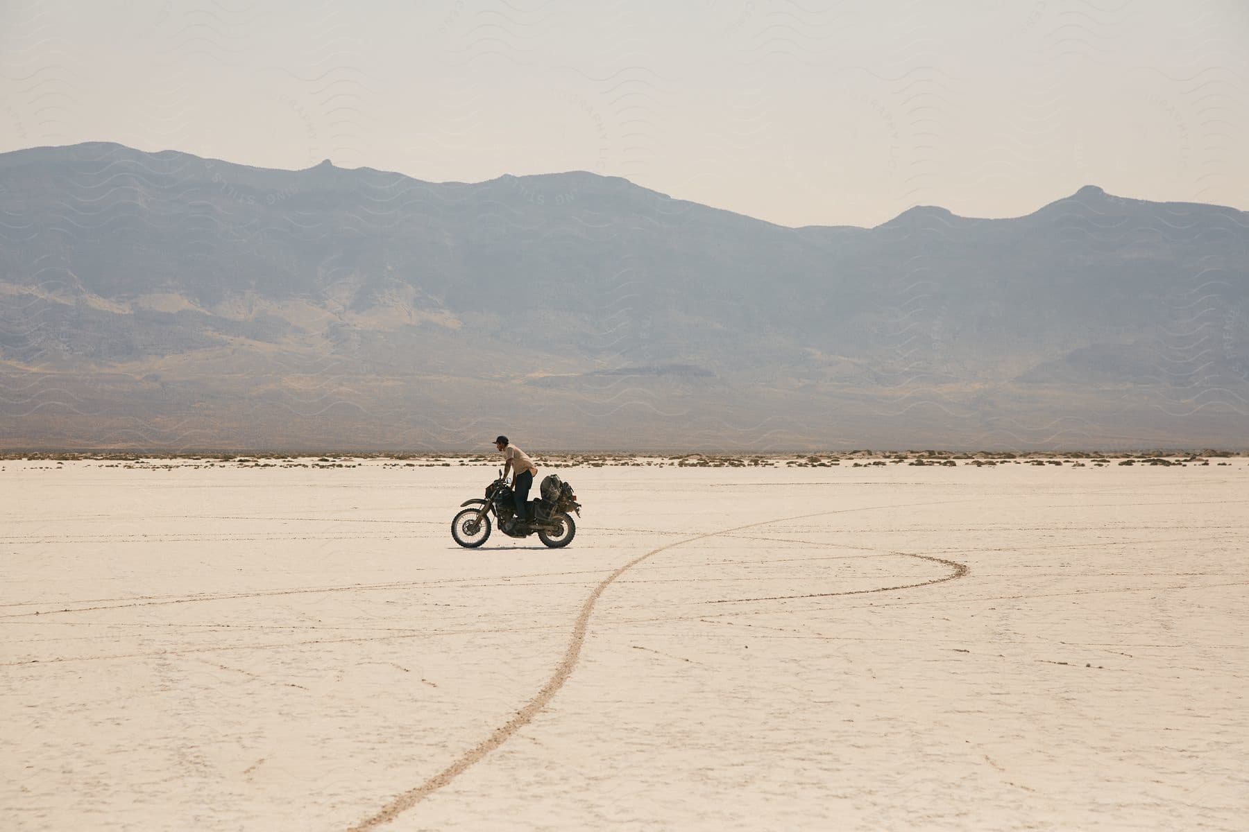 Man riding a motorcycle outdoors in the desert next to a mountain