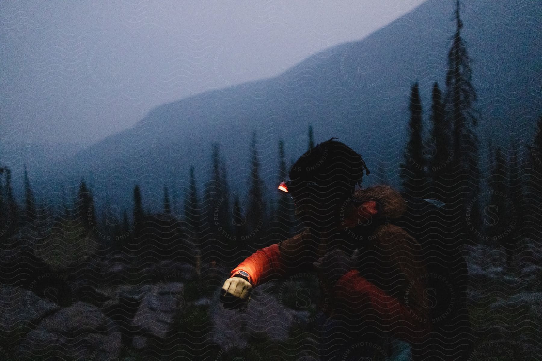 A hiker checks his light up wristwatch on a rocky mountain path at night