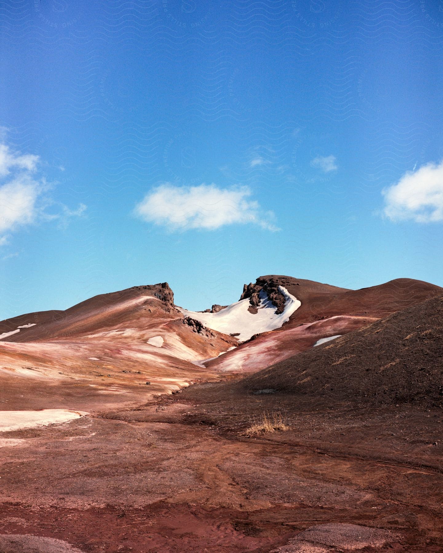 A hill with a valley in the center is shown beyond other hills and flatlands in iceland