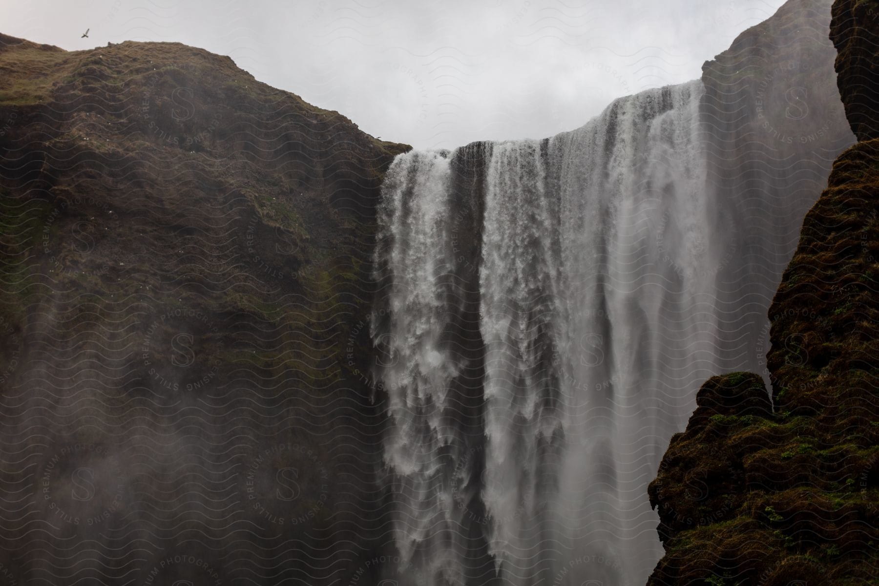 Water cascading from a massive waterfall on a cloudy day at skógafoss in iceland