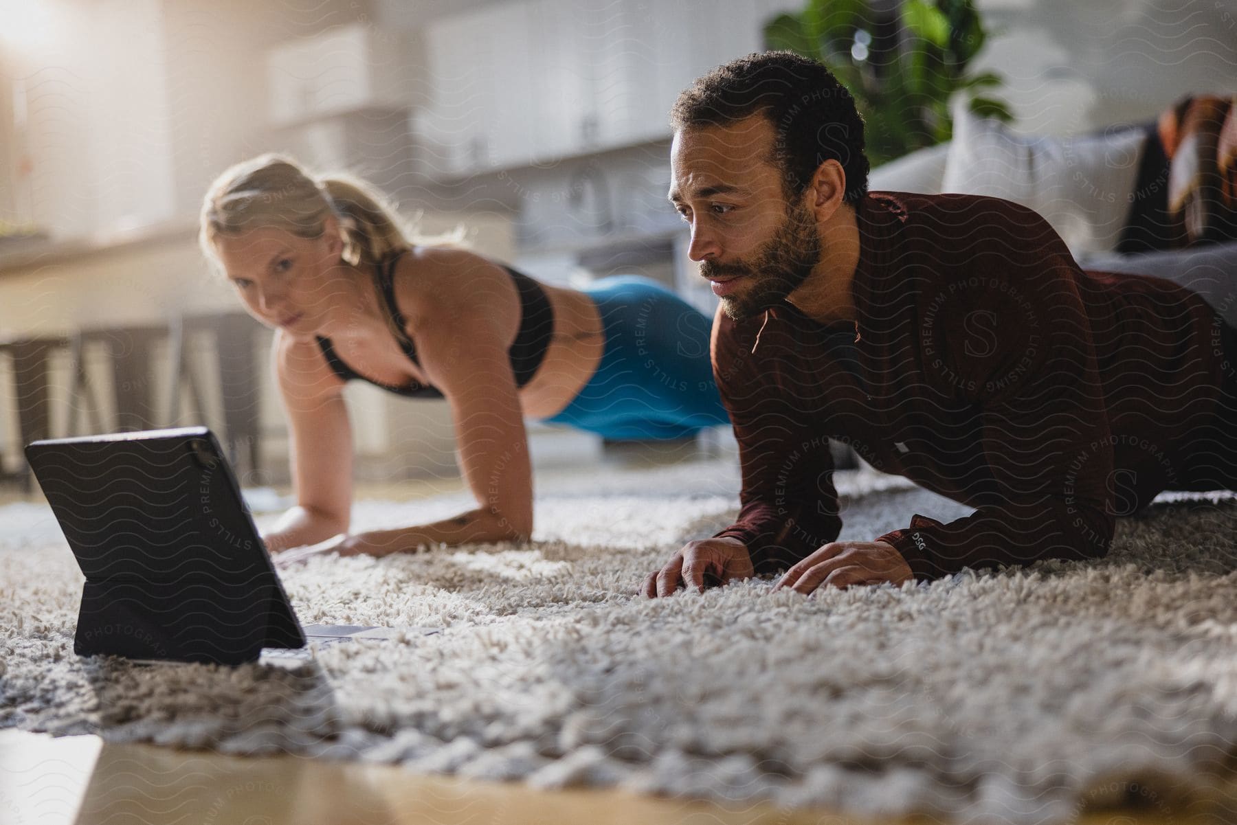 A couple attempts yoga on the floor with a tablet computer