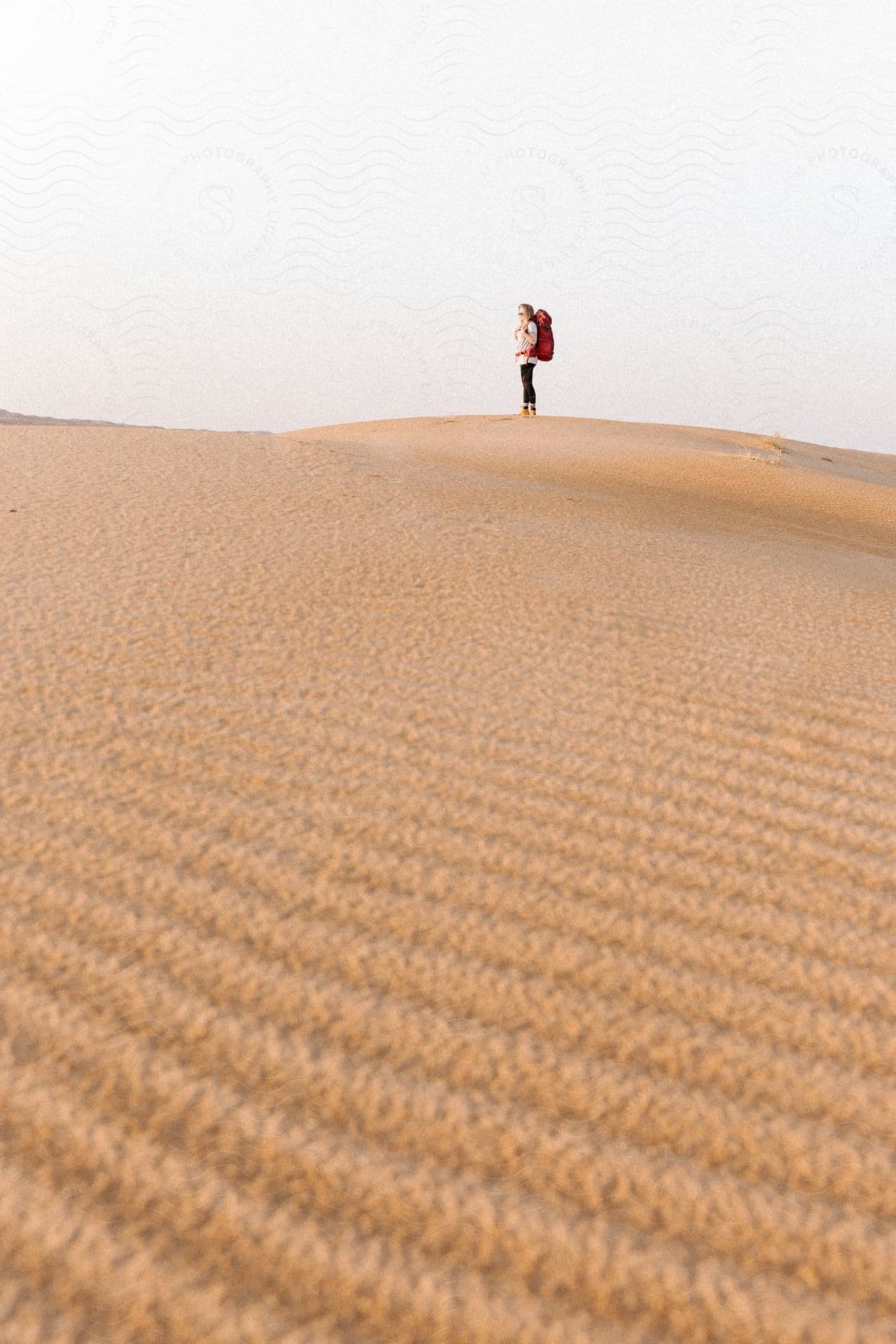 A woman backpacking through the desert during the day