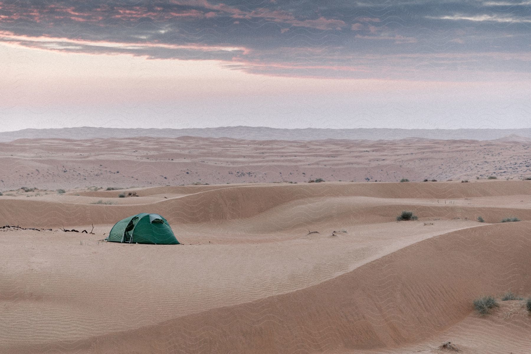 Sandy landscape with a green tent in oman